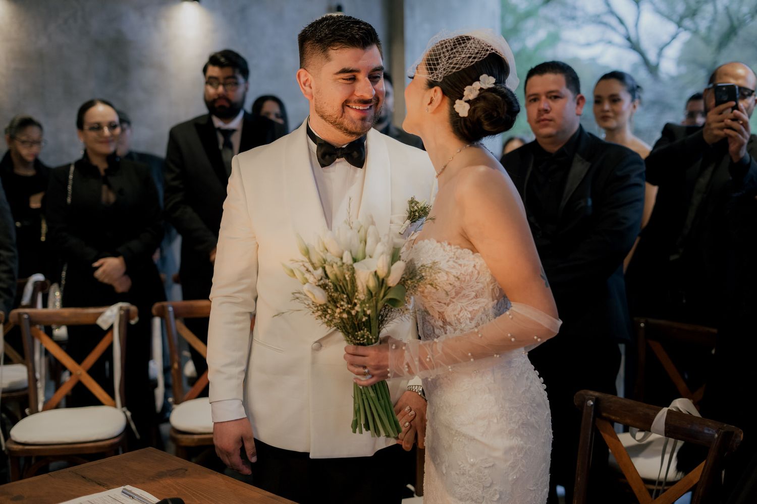 Wedding ceremony gathering in modern industrial-style venue with guests seated.