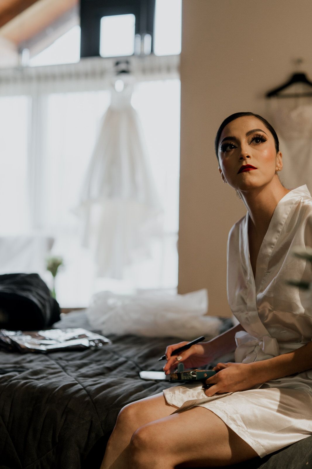 Wedding morning preparation scene with white robe and natural window lighting.
