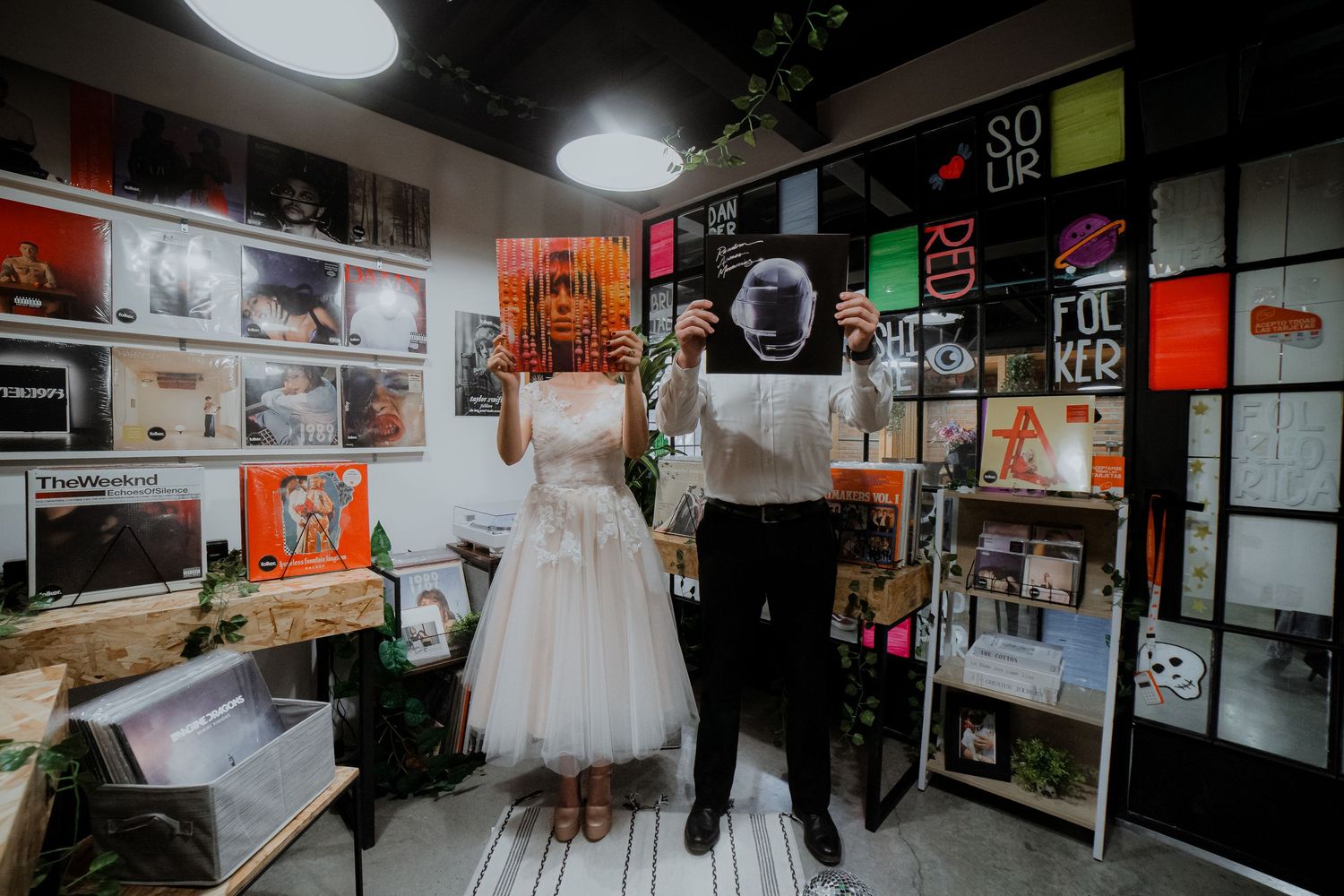 Wedding couple in dark retail space with neon signs and modern decor.