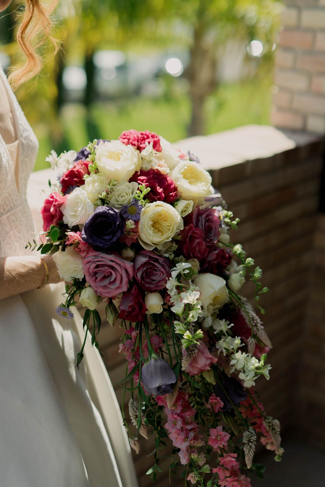 Stunning bridal bouquet featuring pink, purple, and white roses with delicate greenery.