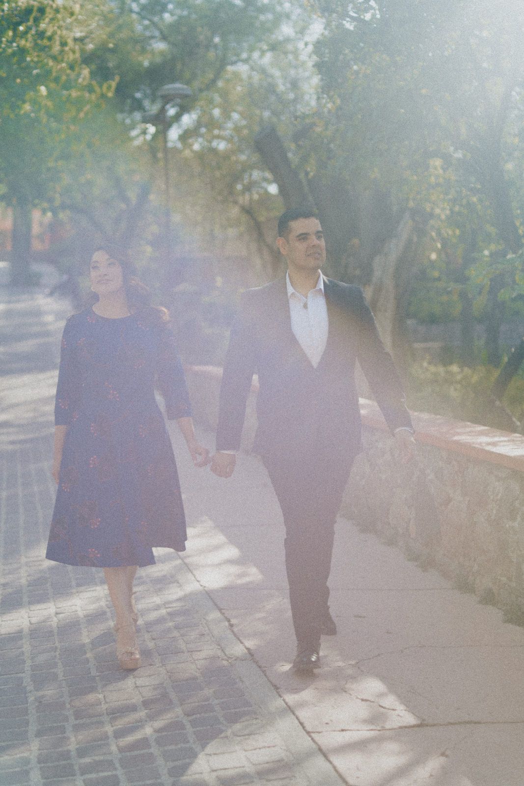 Dreamy sunlit scene of couple walking along stone pathway.