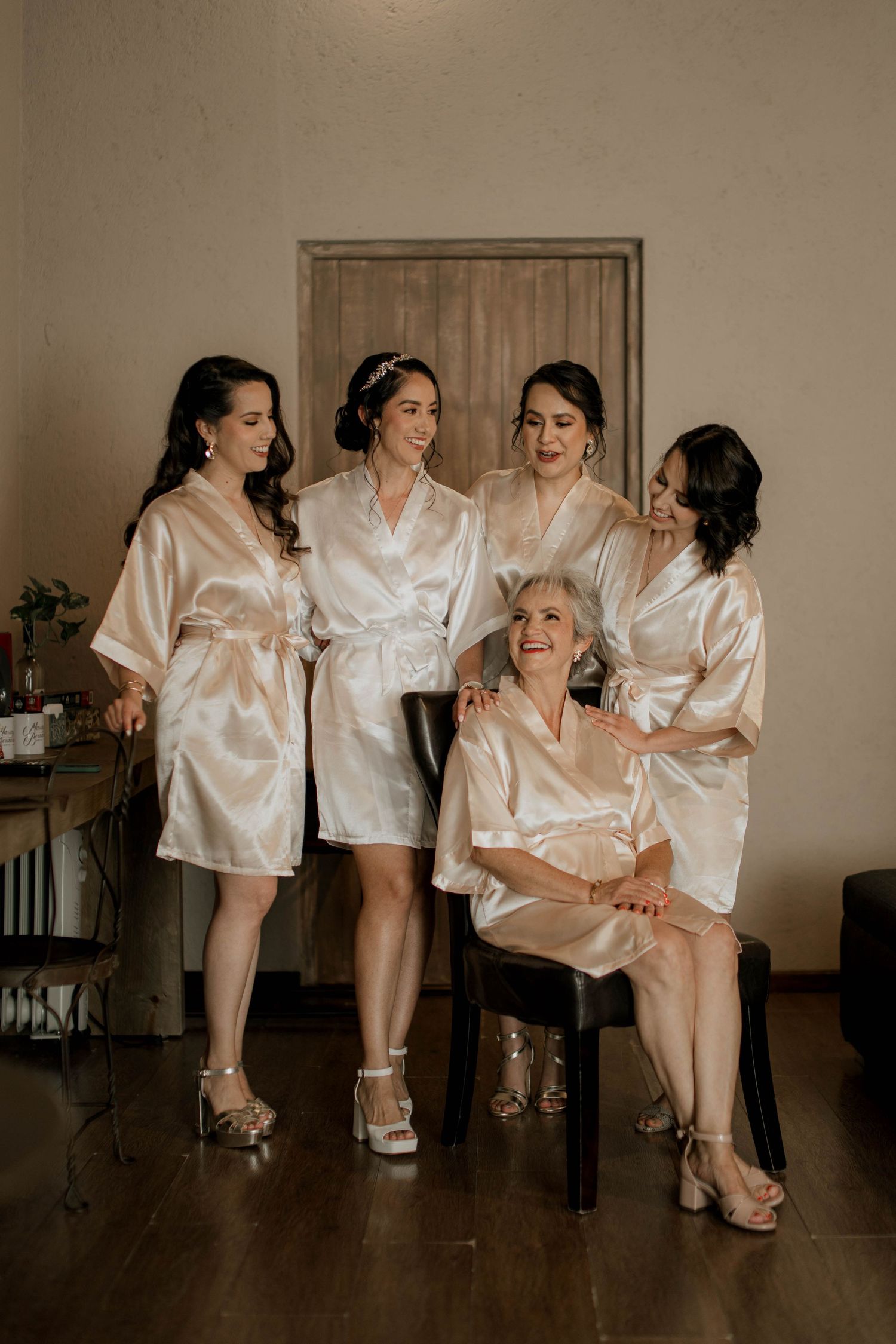 A group wearing matching silk robes poses playfully in a stylish indoor setting.