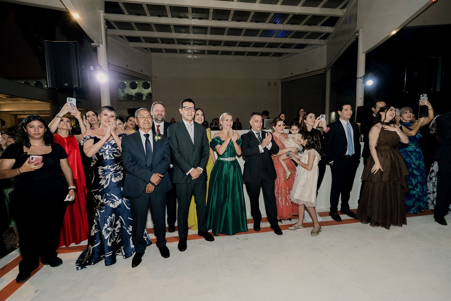 Wedding guests in formal attire watch and celebrate on the dance floor during a reception event.