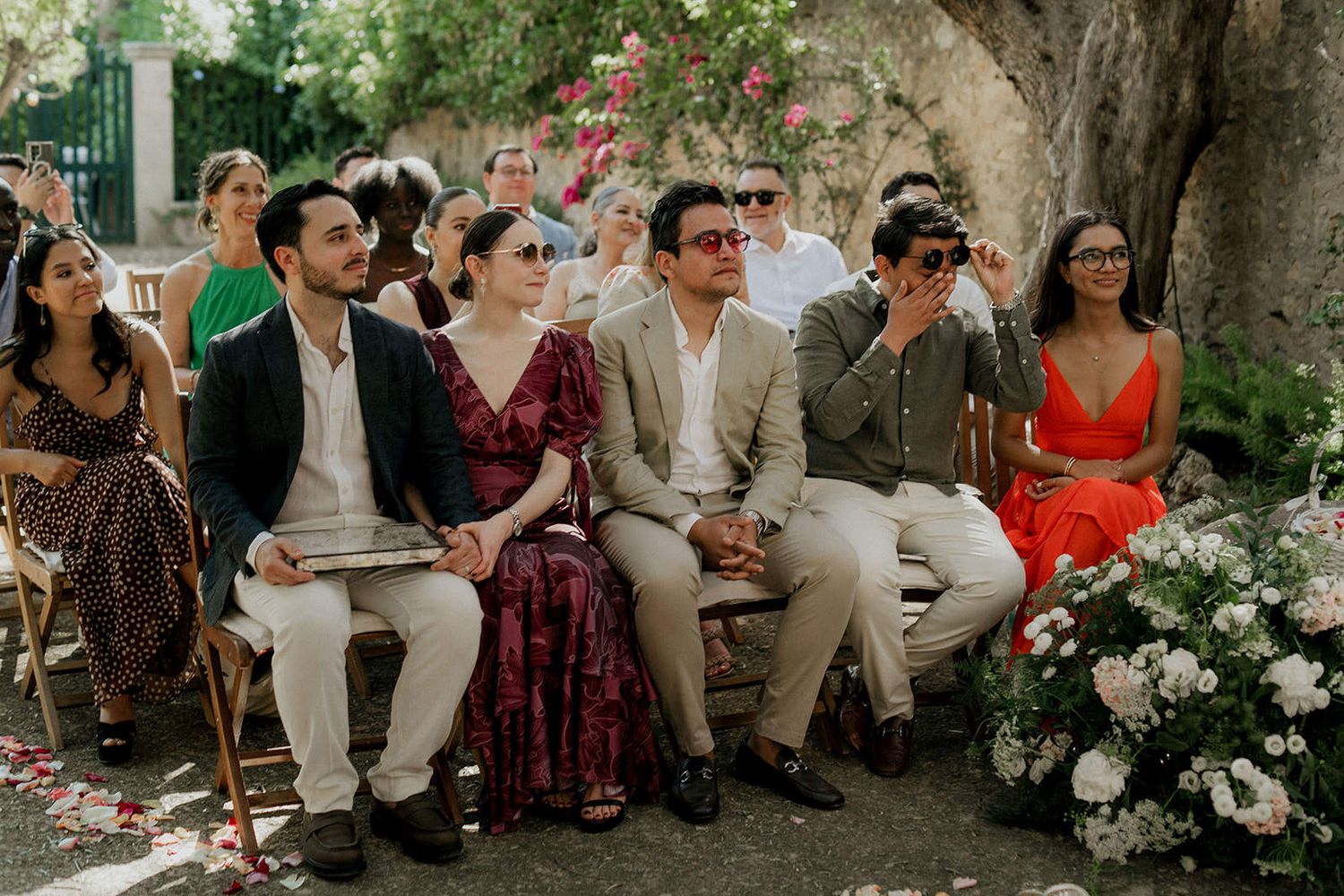 Wedding guests seated outdoors in casual attire during a garden ceremony celebration.