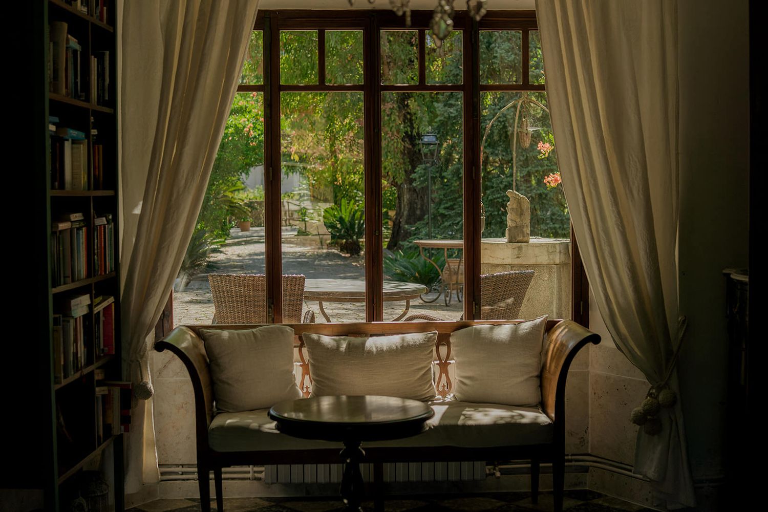 Elegant living room interior with large windows, beige curtains, and comfortable seating bathed in natural light.