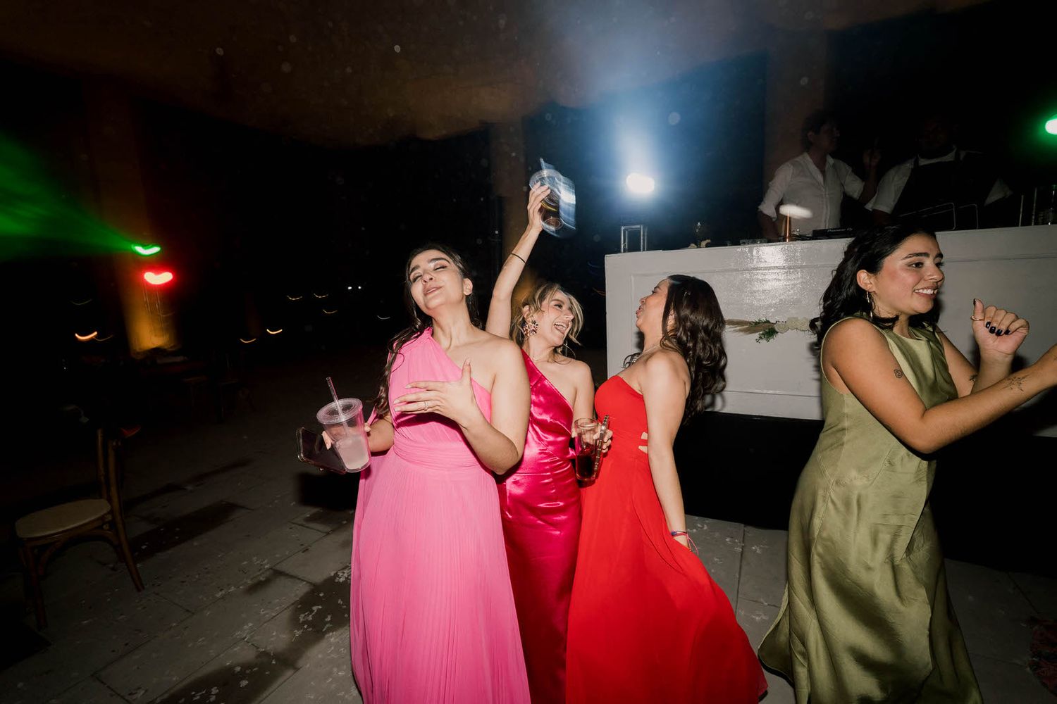 Guests in bright dresses dancing and celebrating at a nighttime event.