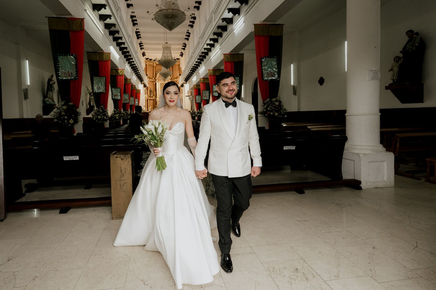 Wedding party walking down a modern church aisle with white columns.