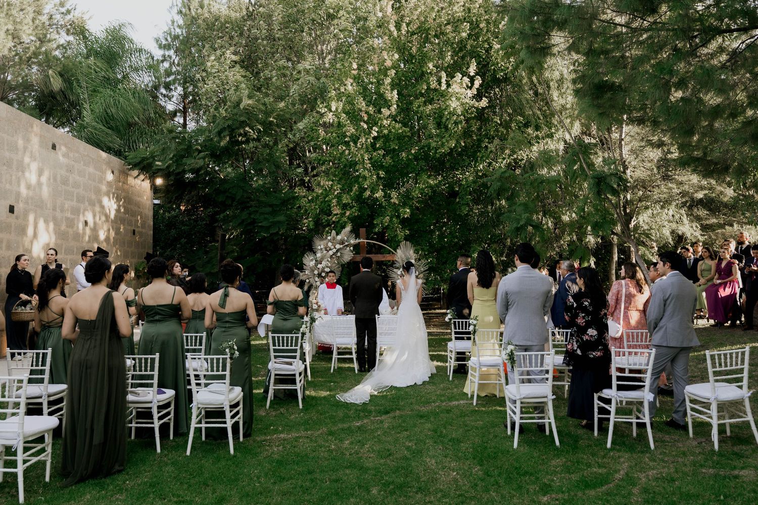 White chairs arranged in rows for an outdoor wedding ceremony under trees.