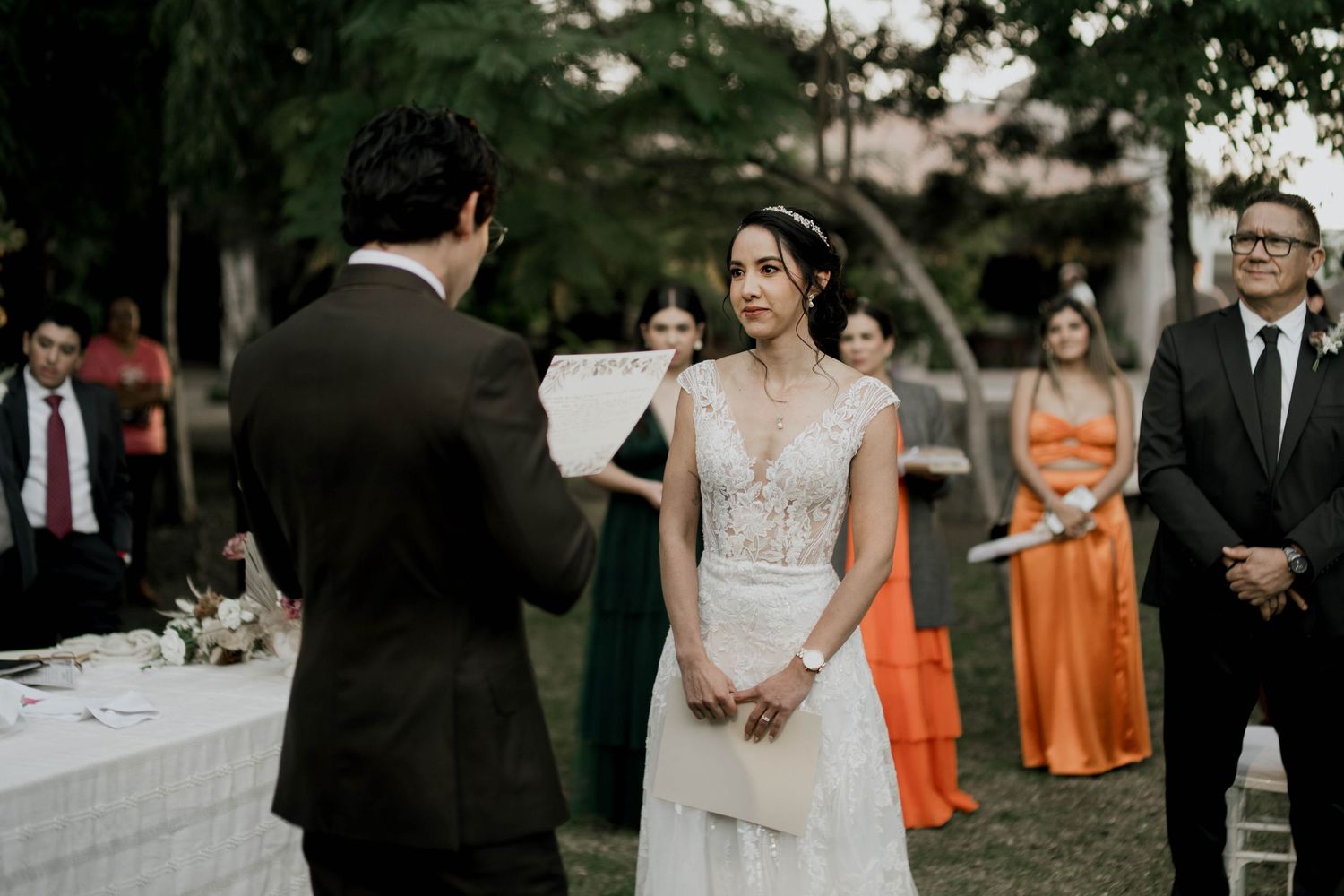 Wedding party and guests gather for an outdoor celebration with orange and purple accents.