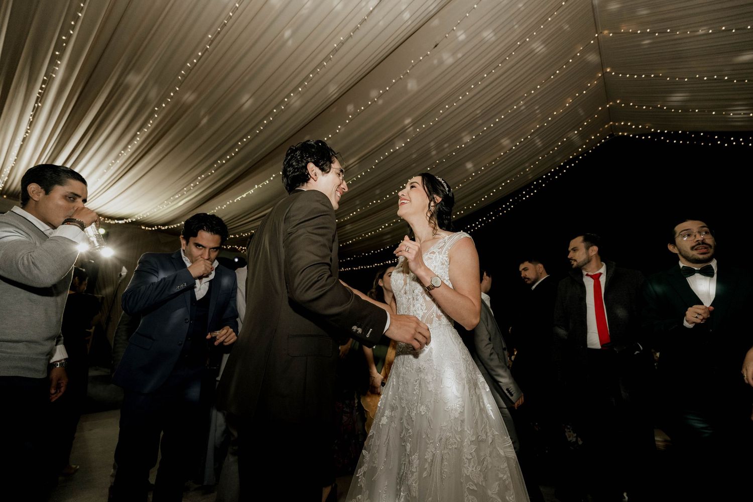 Couple sharing a romantic dance moment surrounded by sparkler effects at an indoor wedding reception.