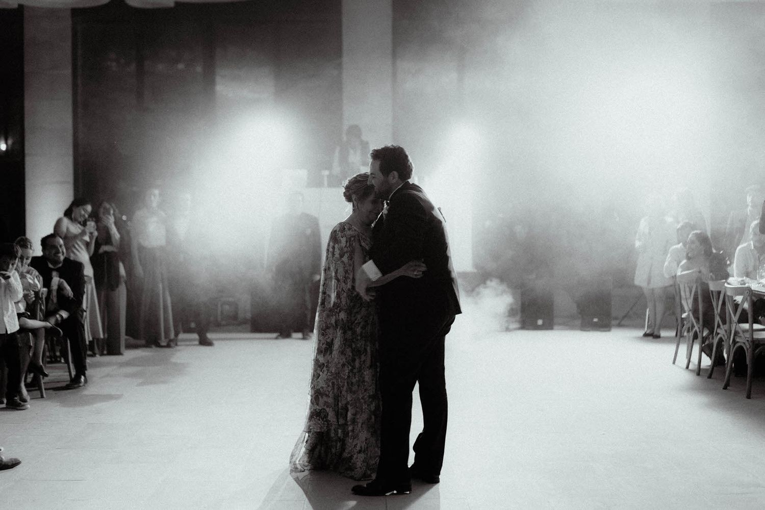 Atmospheric black and white shot of couples dancing at a wedding reception.