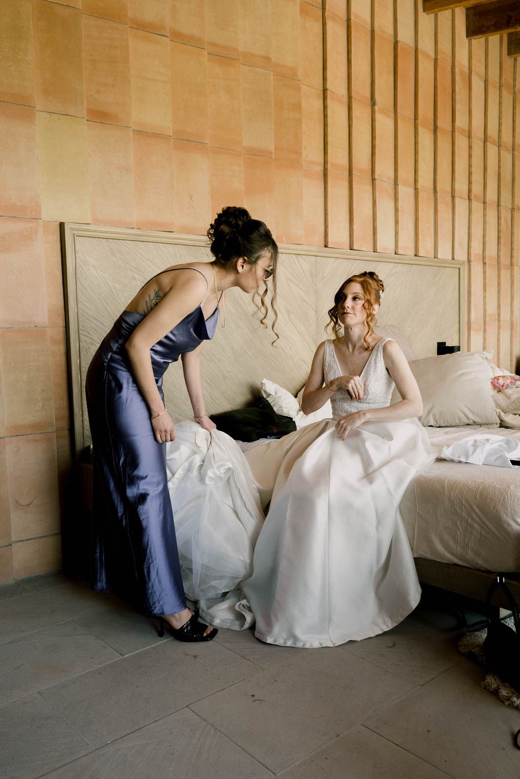 Two people working with white fabric near a couch in an indoor setting.