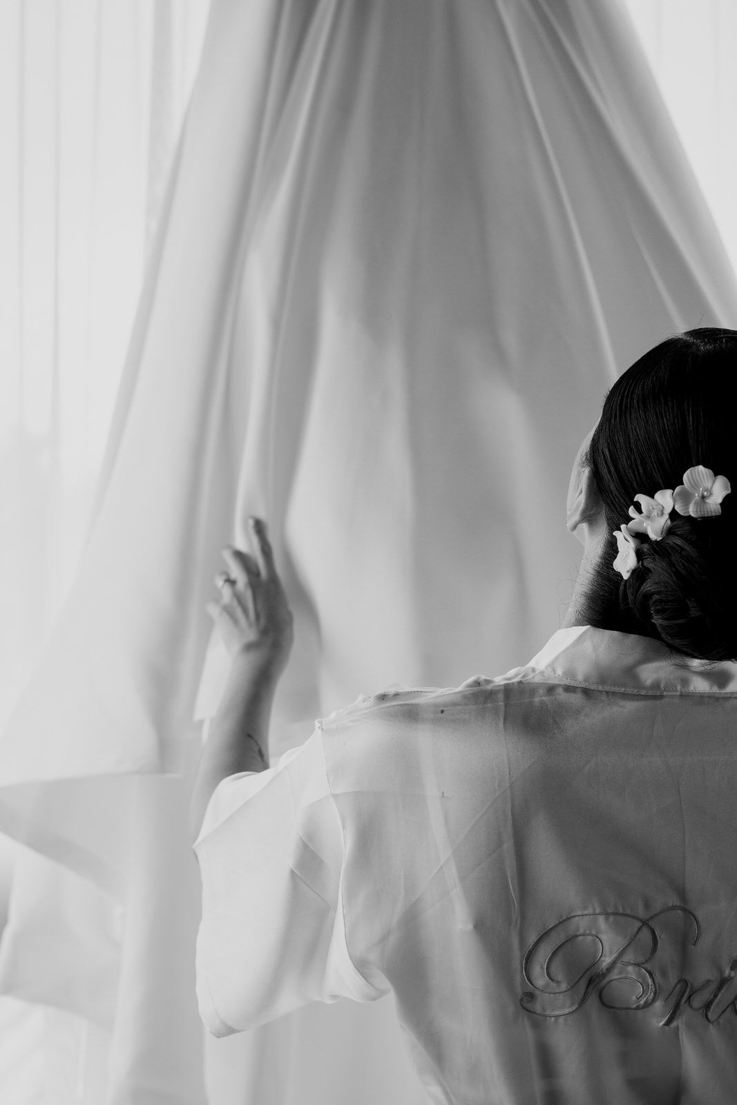 Silhouette through sheer white curtains showing embroidered robe detail.