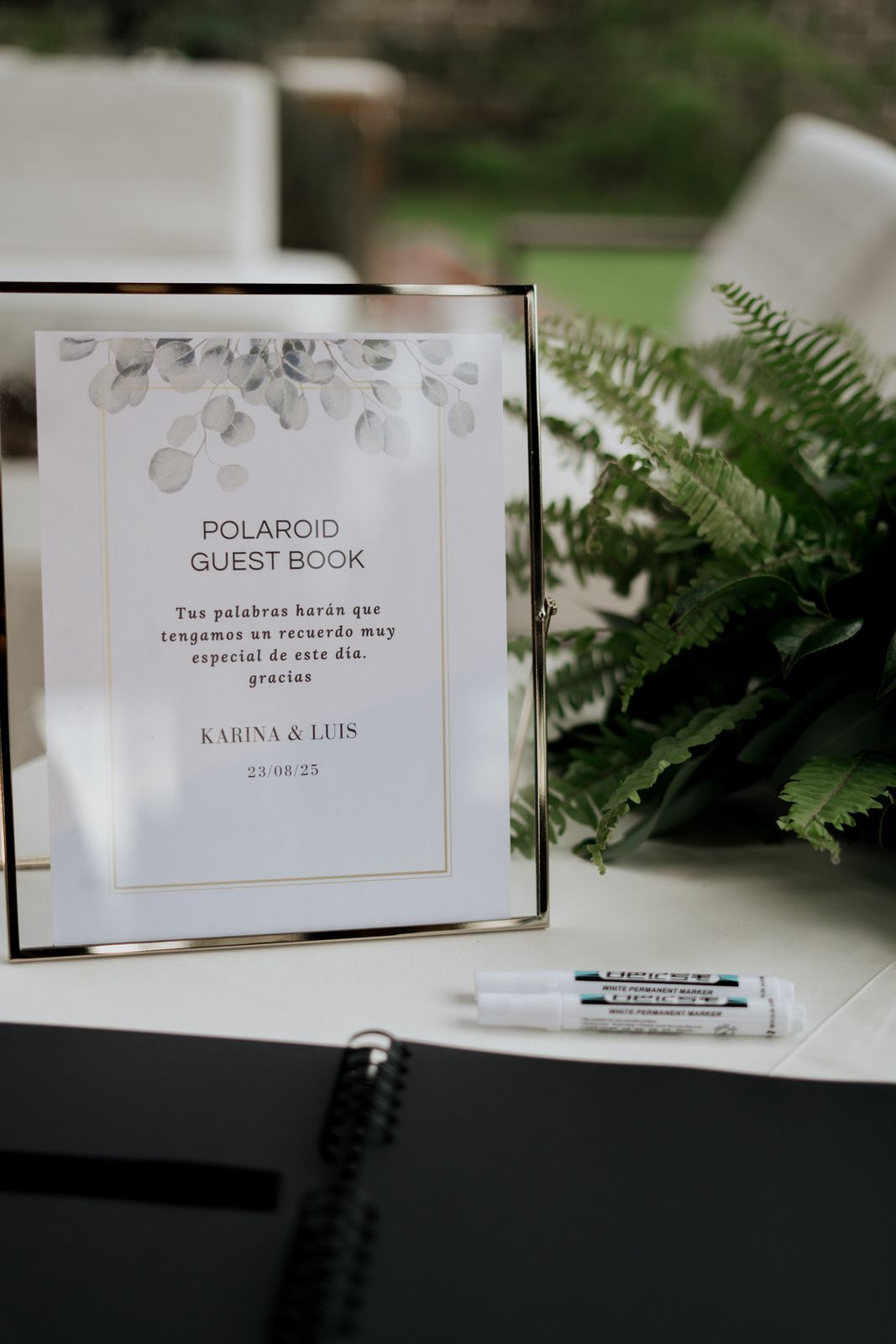 Polaroid guest book sign displayed with ferns and elegant minimalist design.