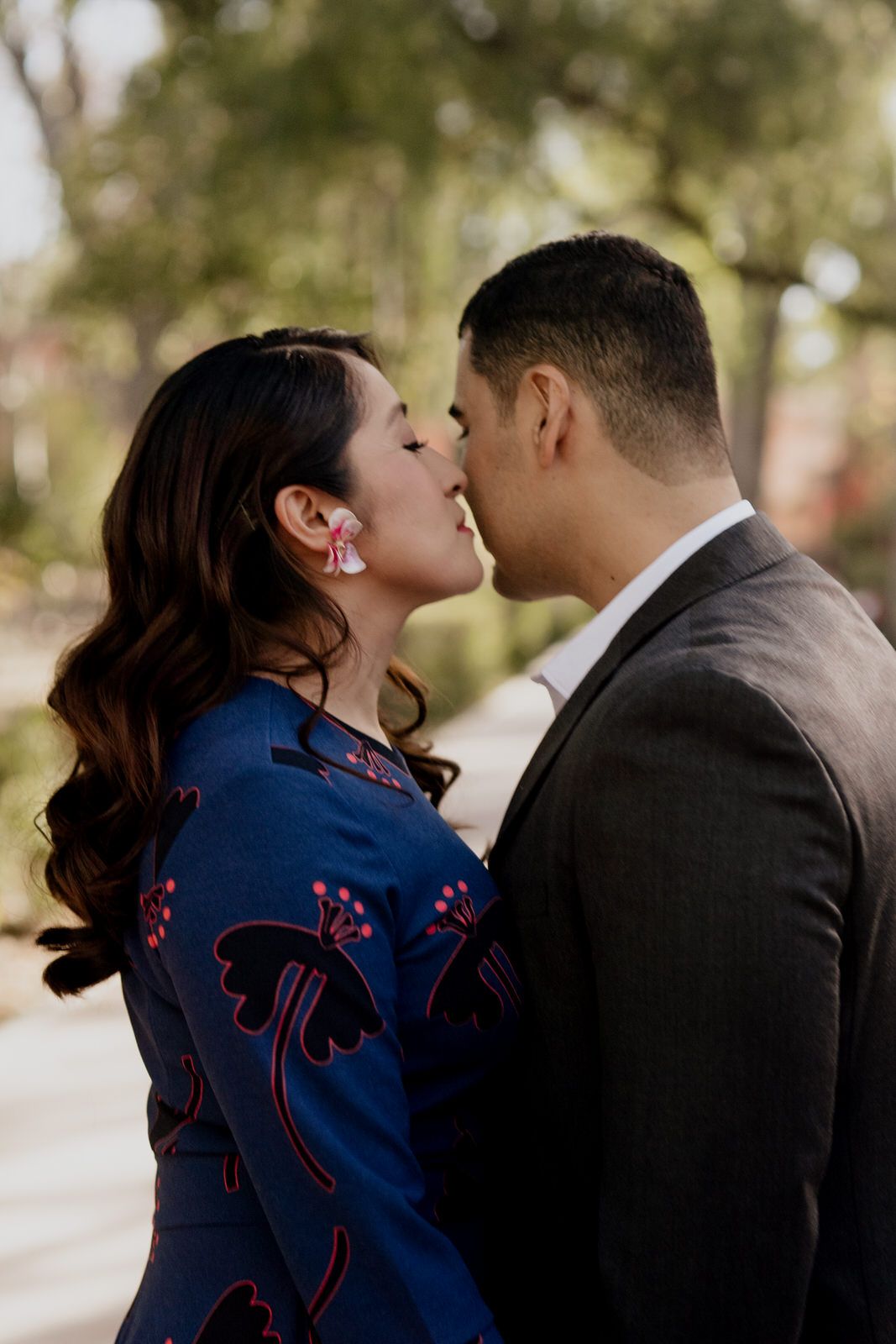 A romantic moment captured between a couple, with the woman wearing a navy blue patterned dress.
