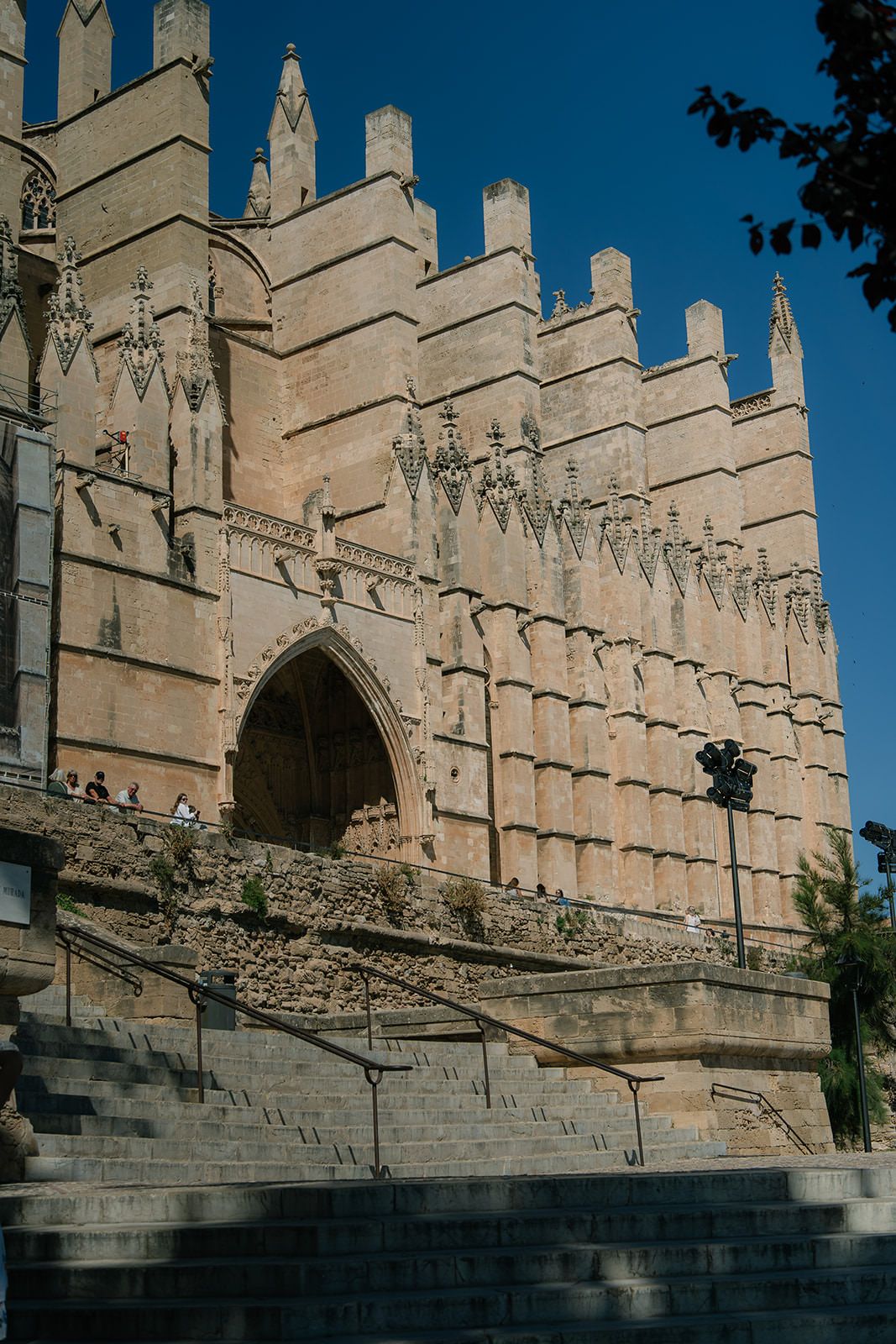 Gothic cathedral facade with ornate stone carvings and pointed arches stands against a blue sky.