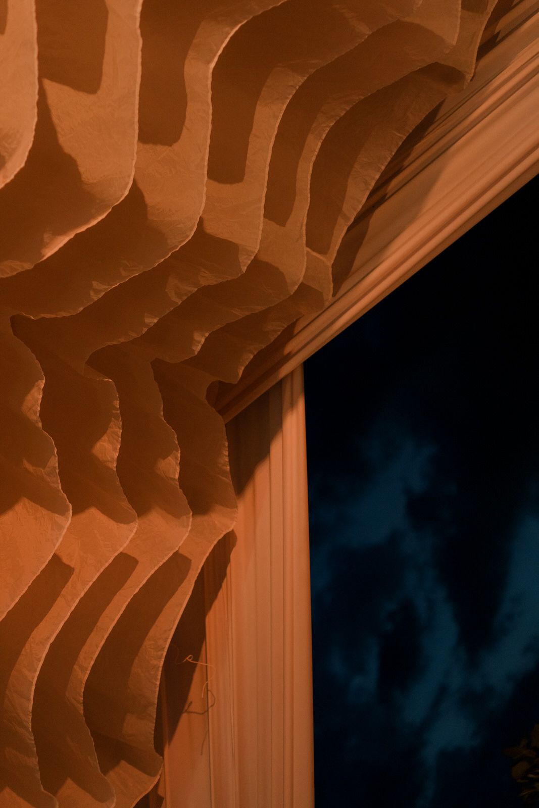 Close-up of decorative wavy orange acoustic panels beside a dark doorway with dramatic lighting.