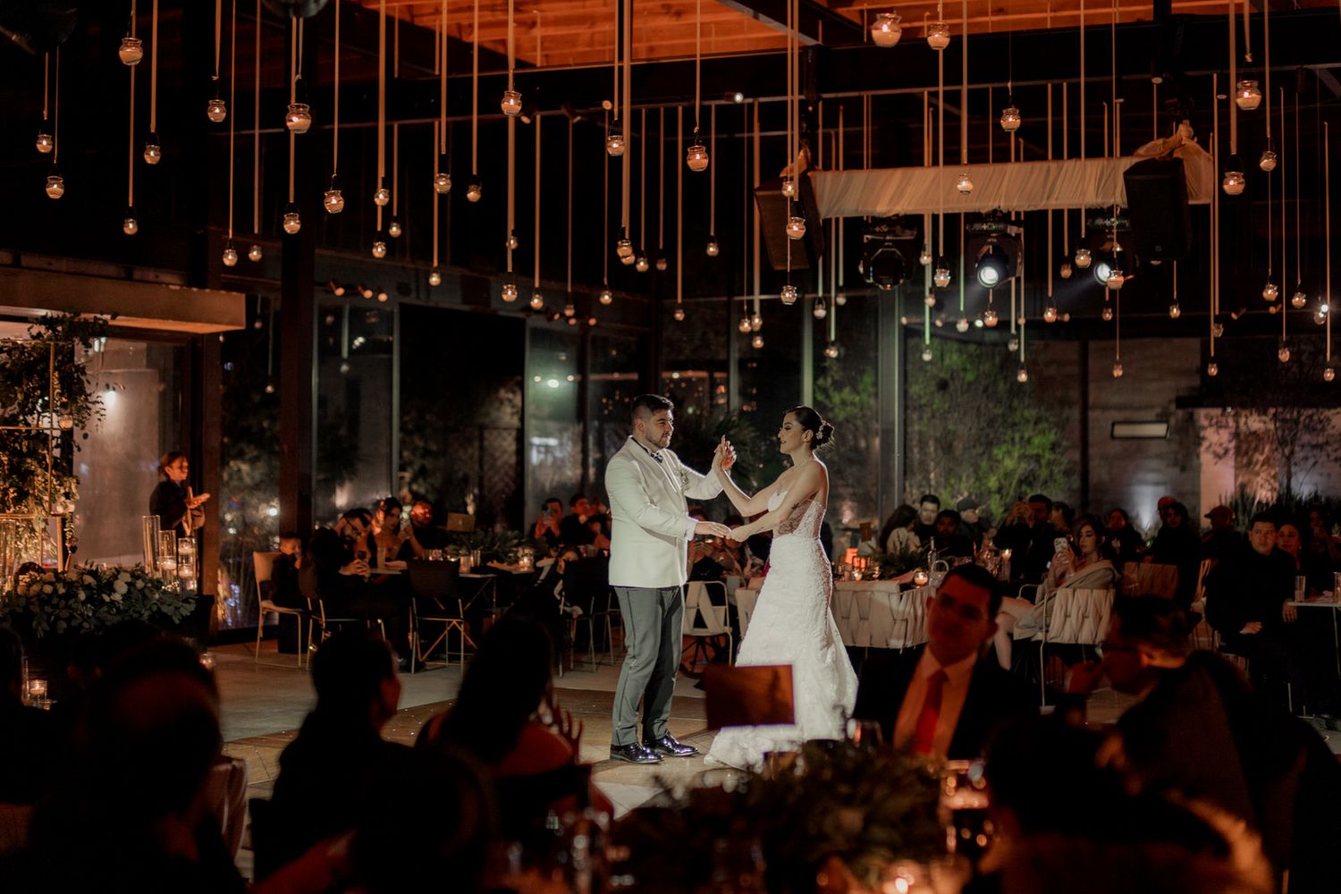 A wedding reception venue with hanging lights and sparklers creating a magical atmosphere on the dance floor.