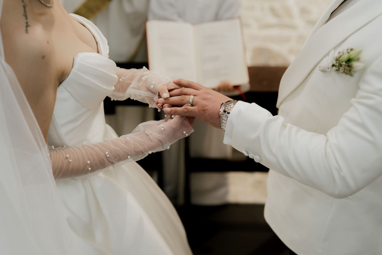 Close-up of wedding ring exchange between bride and groom during church ceremony.