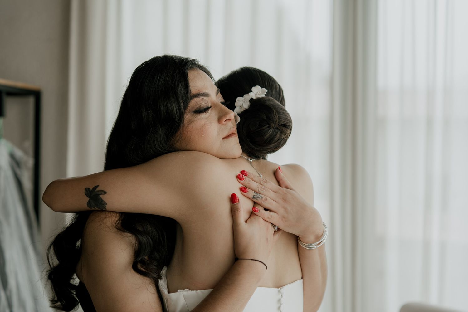 A tender embrace captured in a wedding moment with flowing white dress and dark hair.