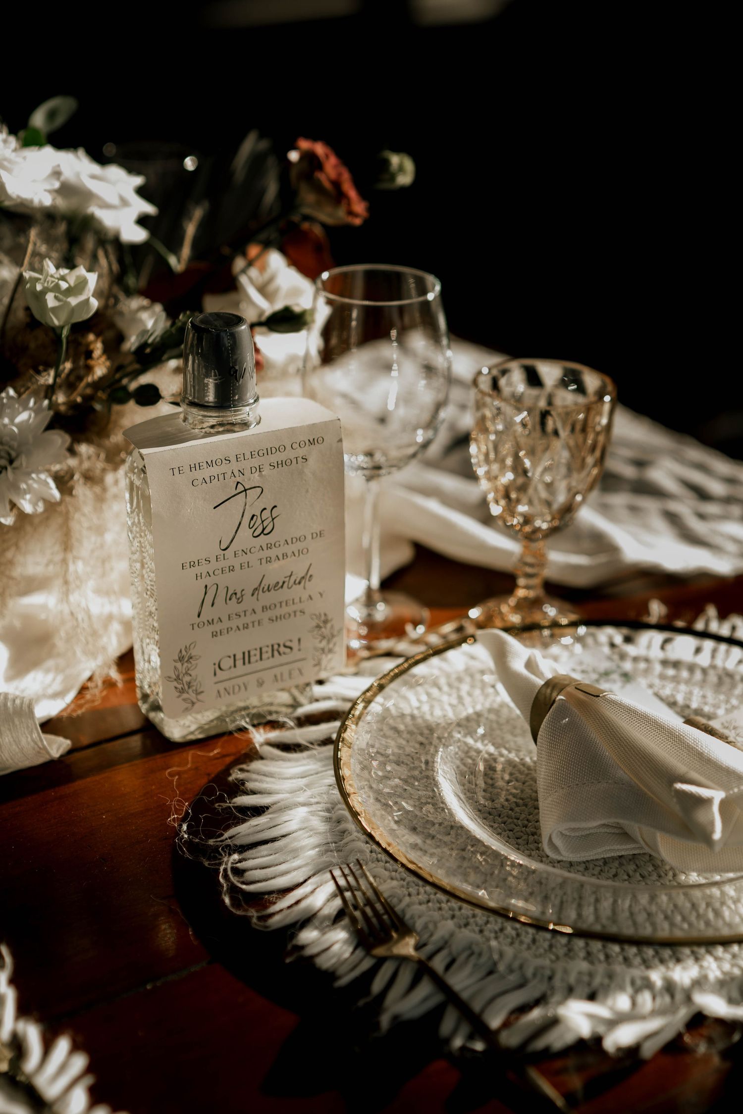 Elegant wedding reception table settings with crystal glassware and decorative place cards in warm lighting.