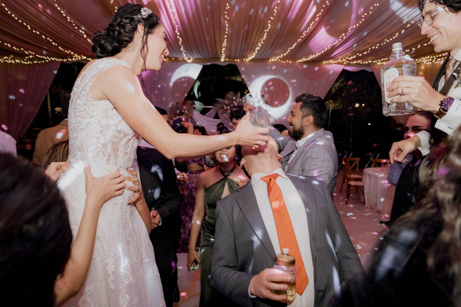 Wedding celebration with bubbles floating through the air under pink string lights.