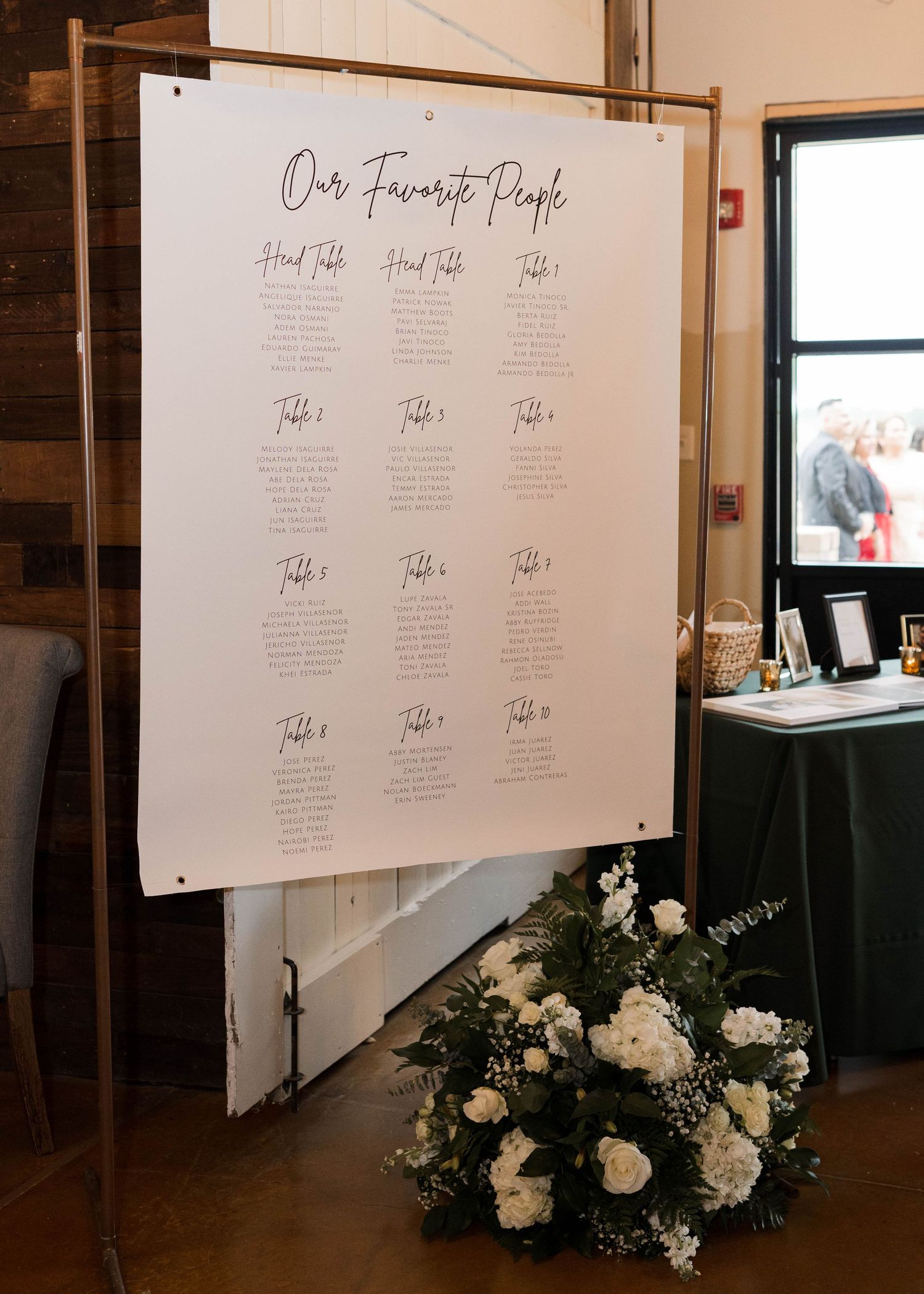 Elegant wedding seating chart titled Our Favorite People displayed on a gold frame stand.