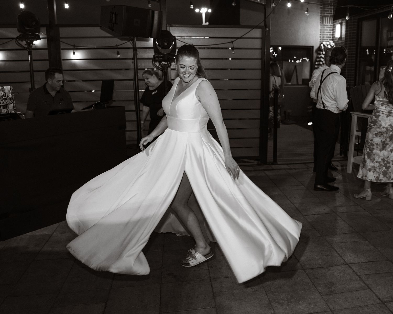 Black and white photo of a bride twirling in her wedding gown on the dance floor at her reception.