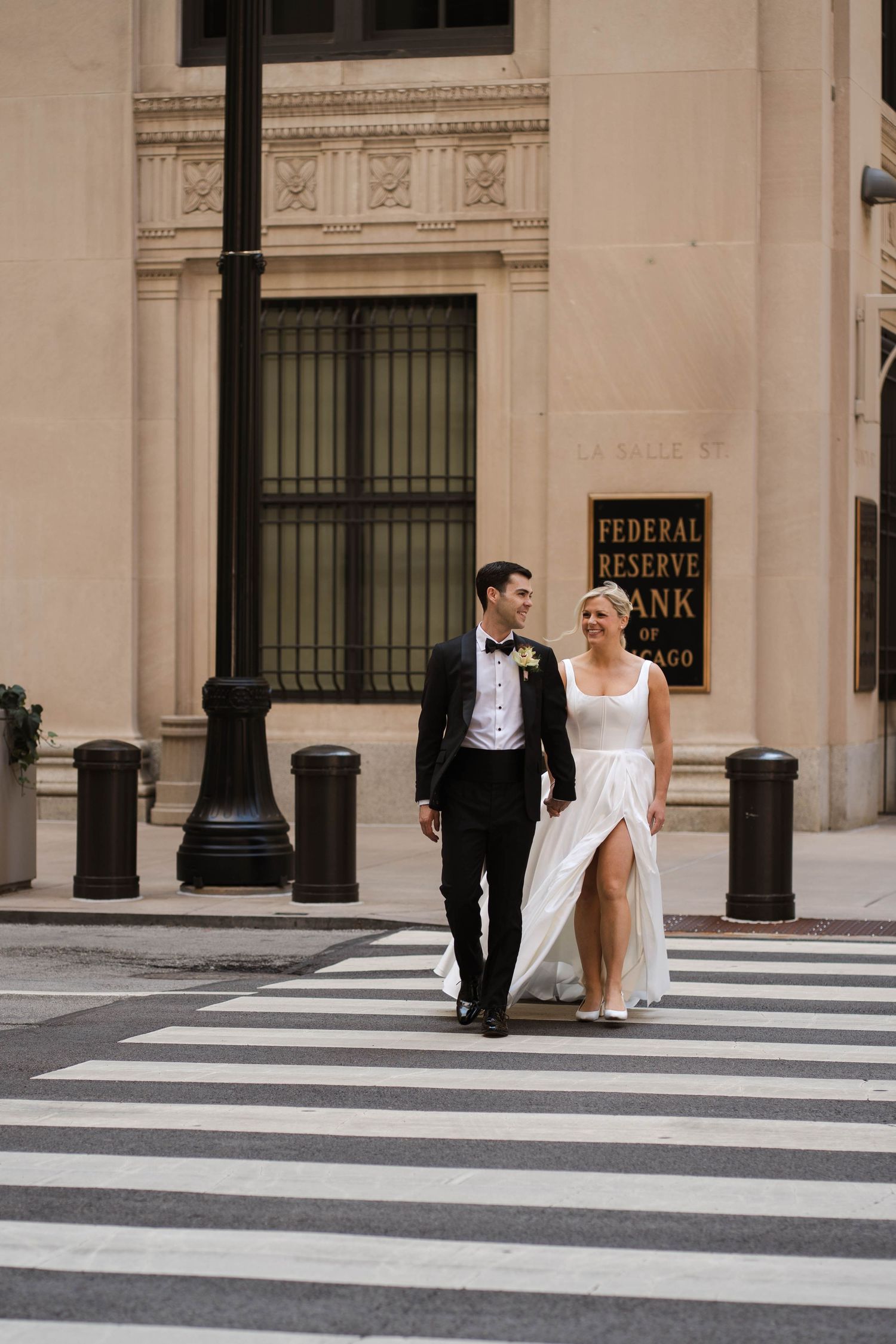 Bride and groom crossing street in front of Federal Reserve Bank of Chicago on their wedding day.
