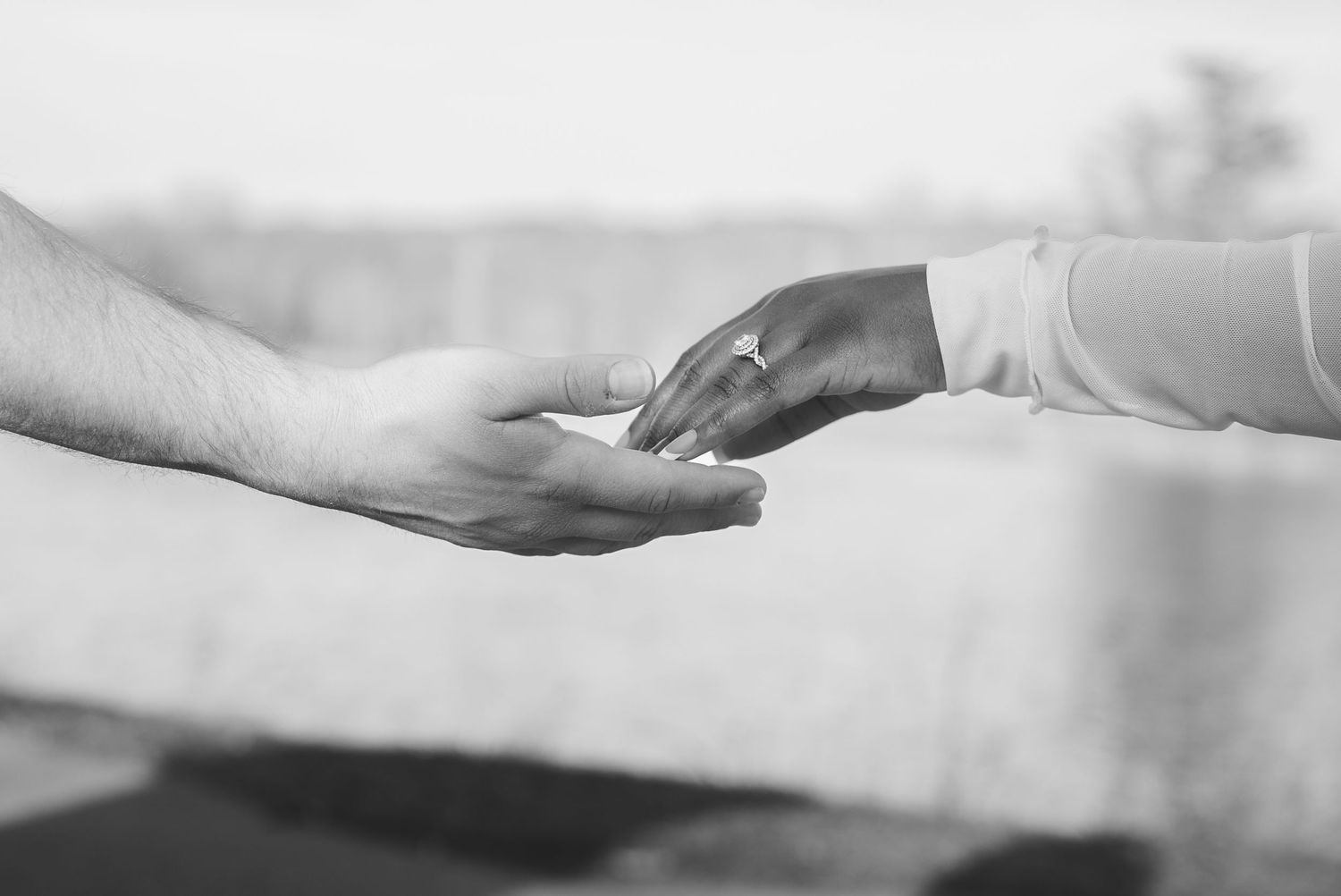 Black and white photo of two hands reaching toward each other in a gentle, caring gesture.
