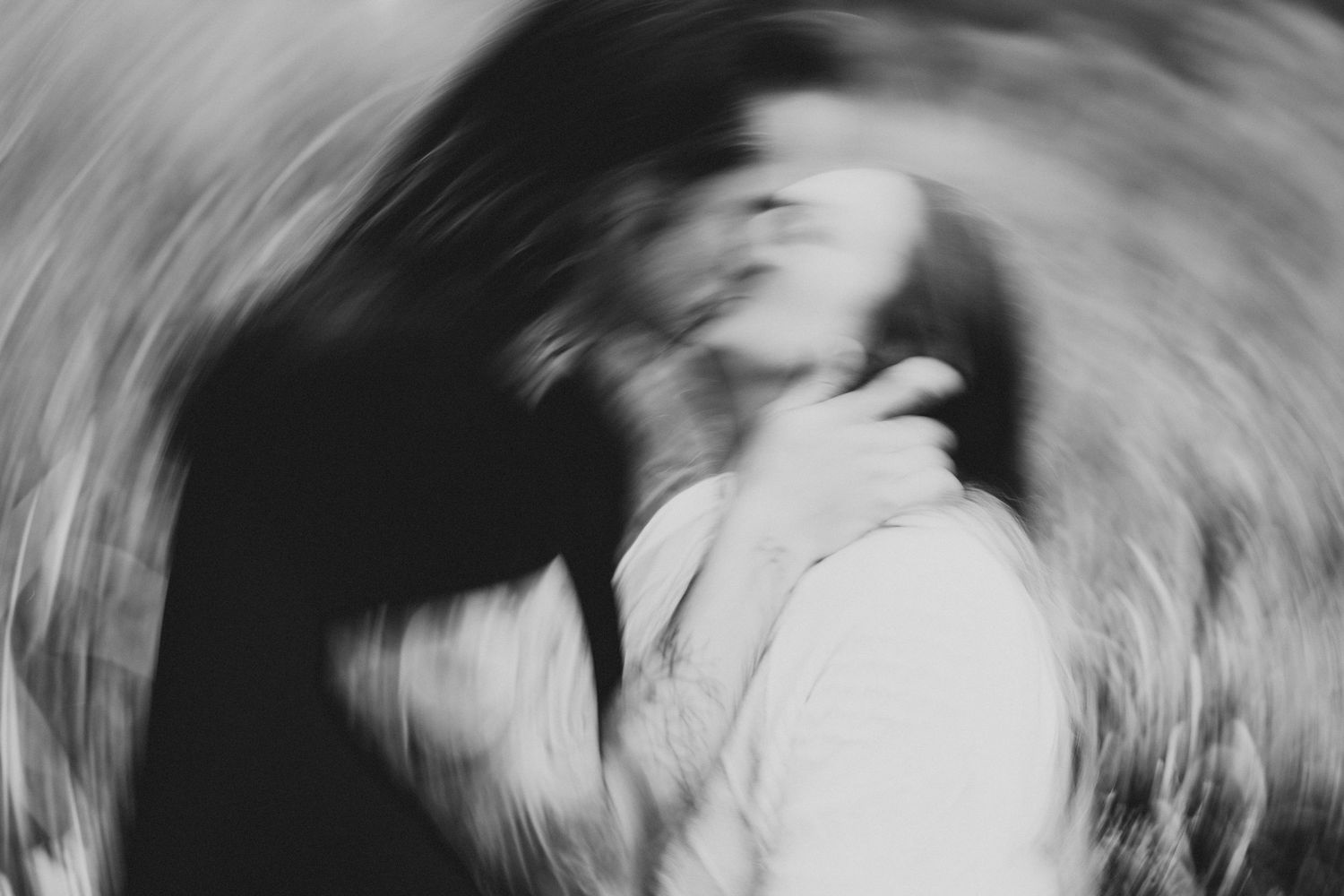Artistic black and white blurred photo of a romantic couple kissing with swirl motion effect.