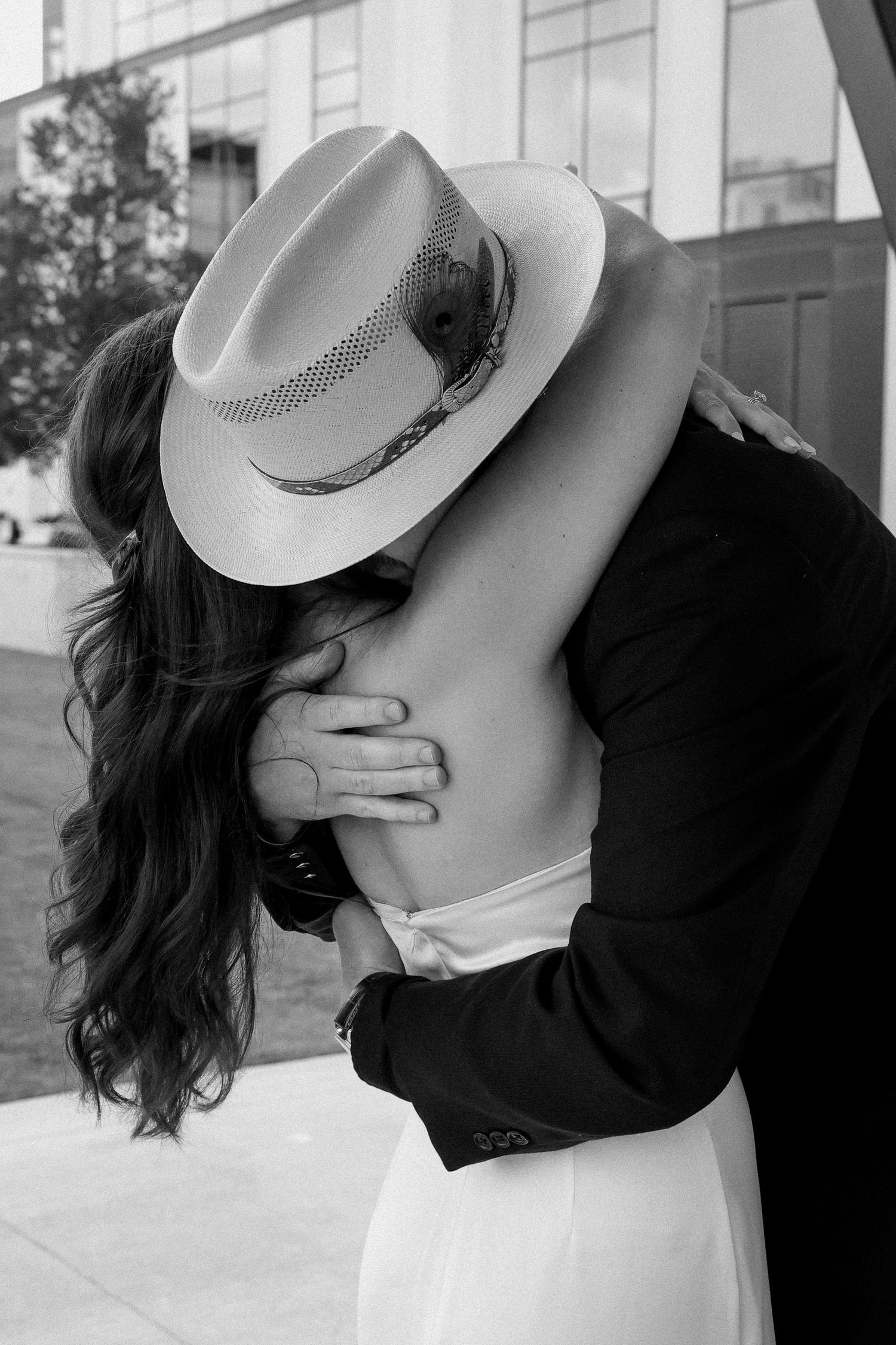 Black and white photo of newlyweds sharing an intimate embrace after outdoor wedding ceremony.