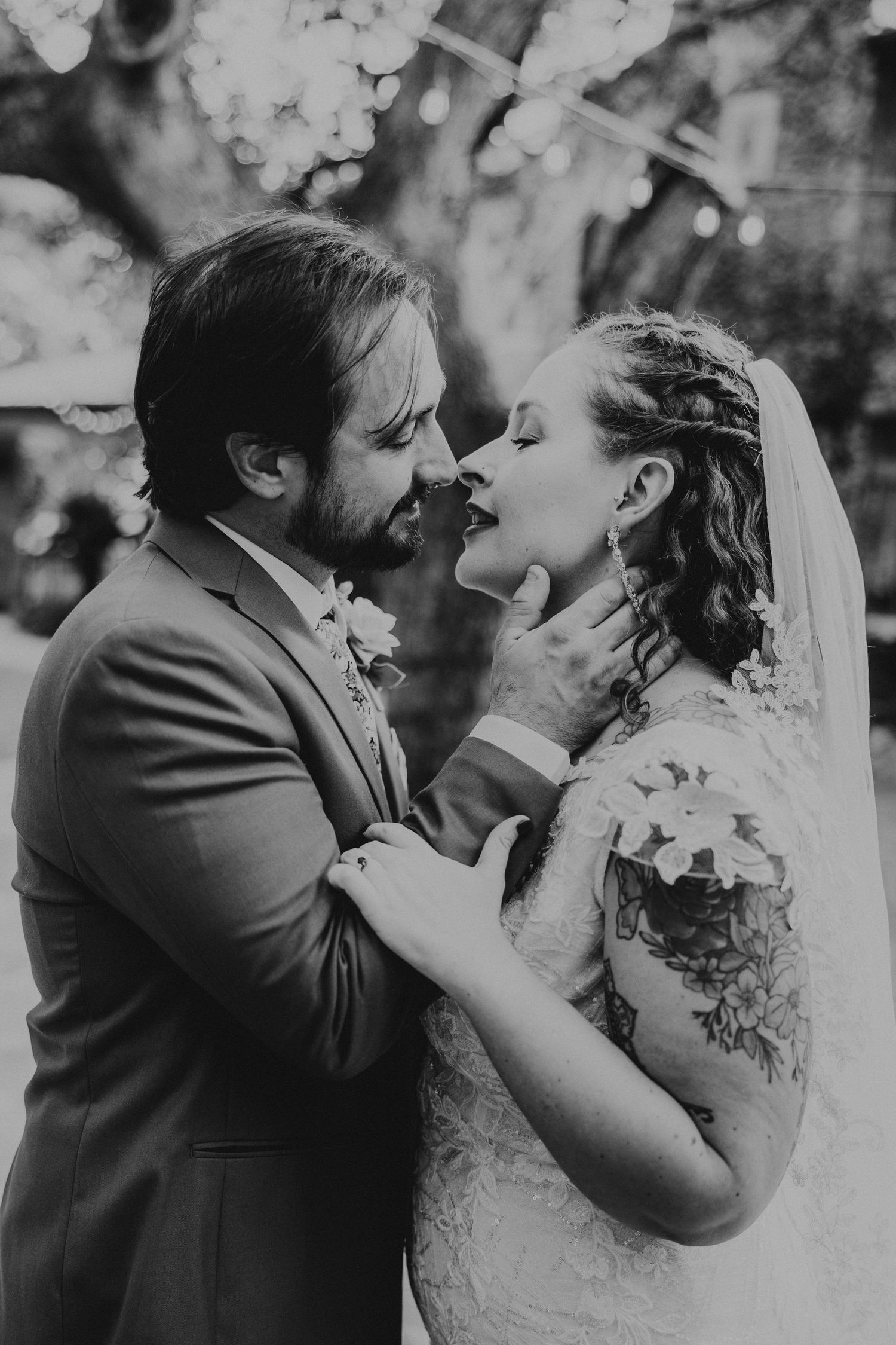 Groom tenderly holds bride's face as they share an intimate moment in a black and white wedding photo.