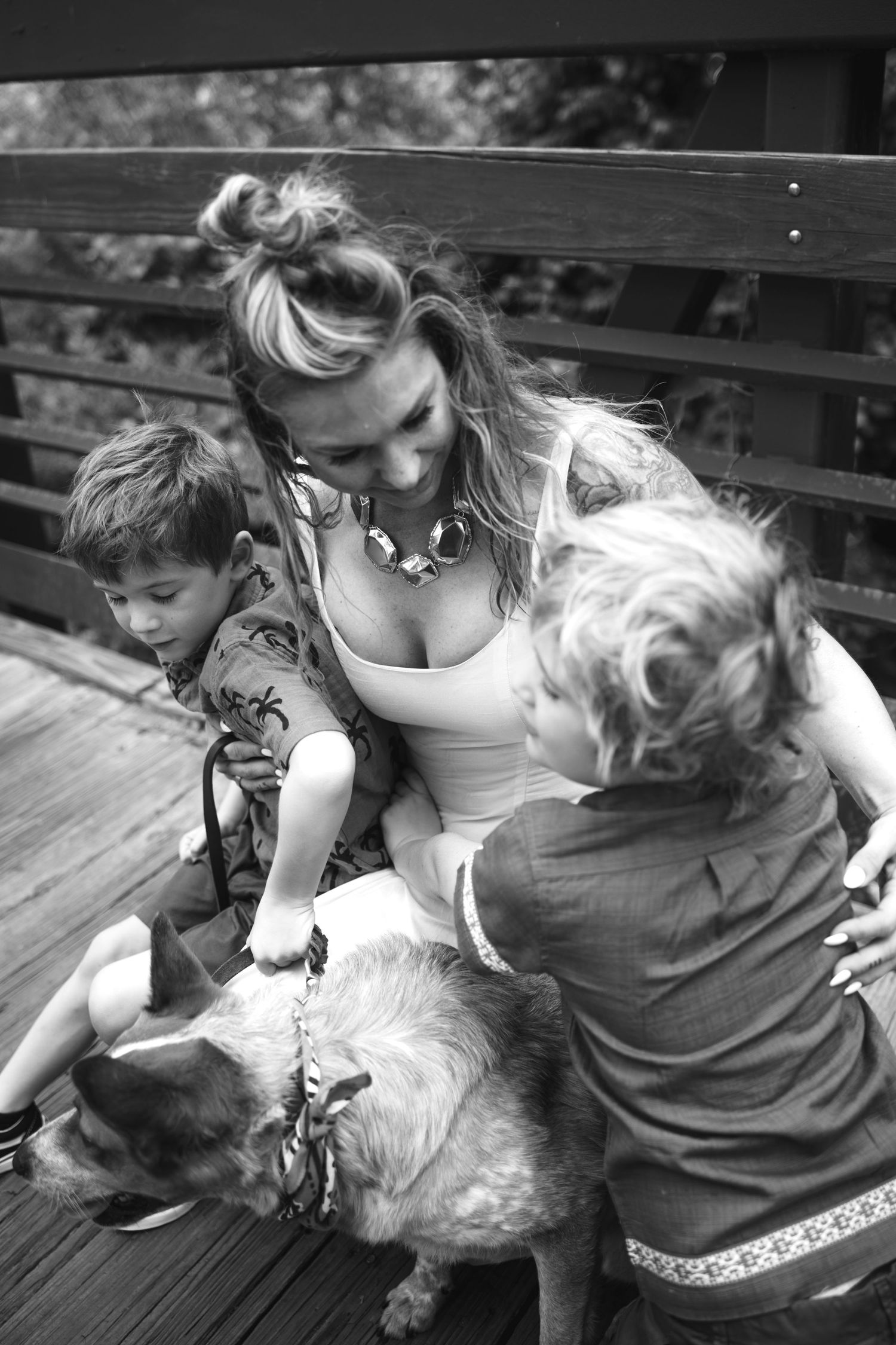 Woman with two children and a dog on a wooden deck in black and white photo.
