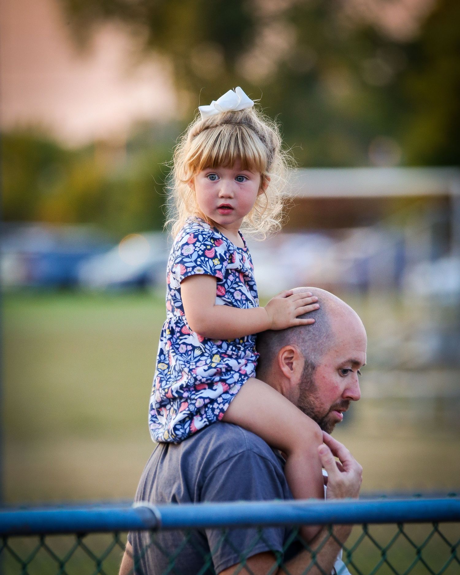 Little girl on her father's shoulders watching a game.