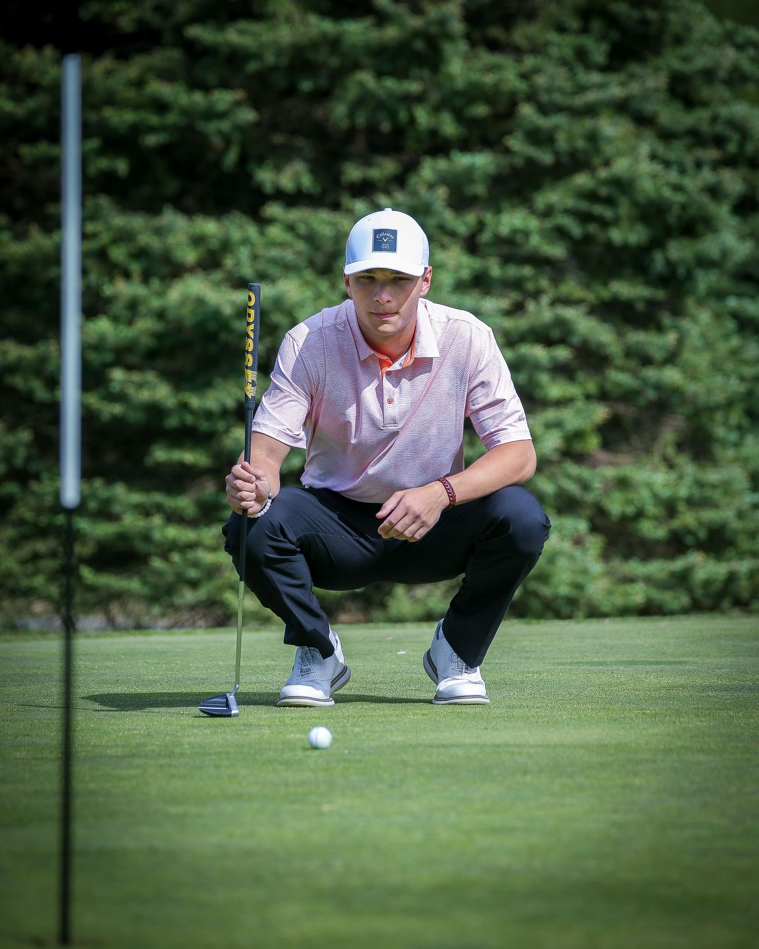 Hightstown High School golf player crouching before a put in Mercer County, New Jersey.