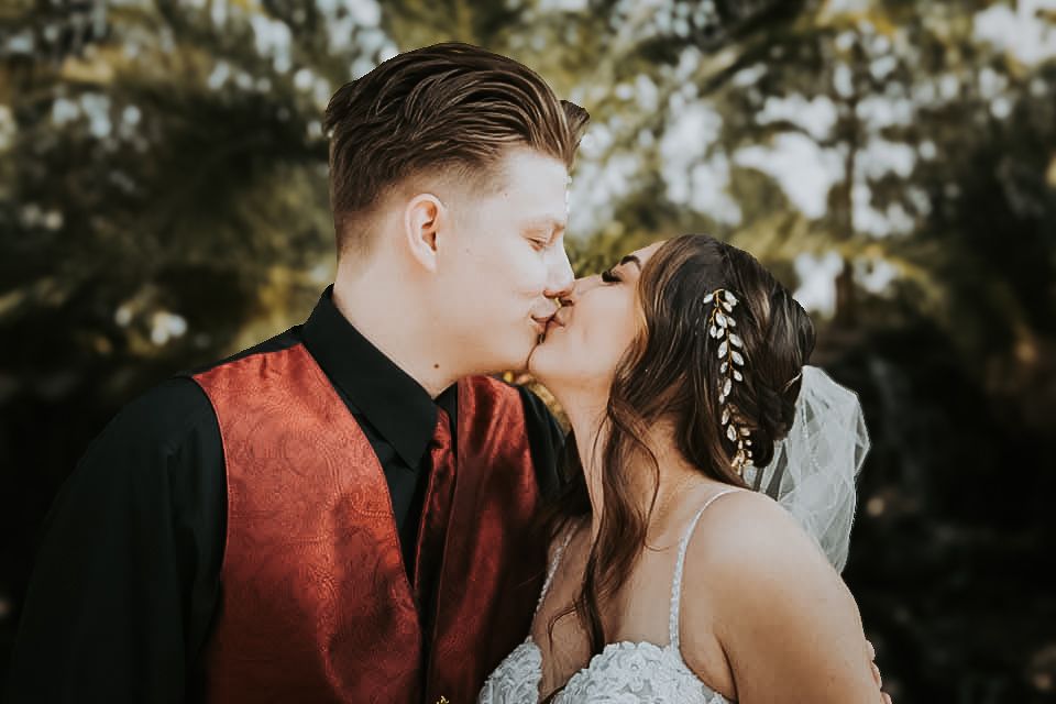 A bride and groom in a romantic embrace, surrounded by nature in the background.