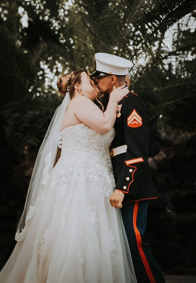 A bride and groom in a romantic embrace at their outdoor wedding ceremony.