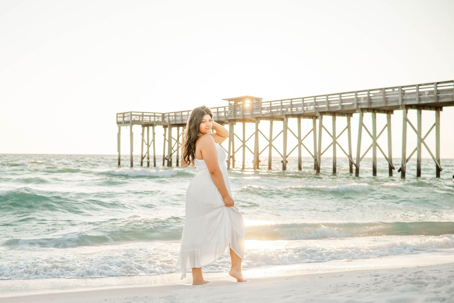 Serene beach scene with golden sunlight streaming through a coastal pier.