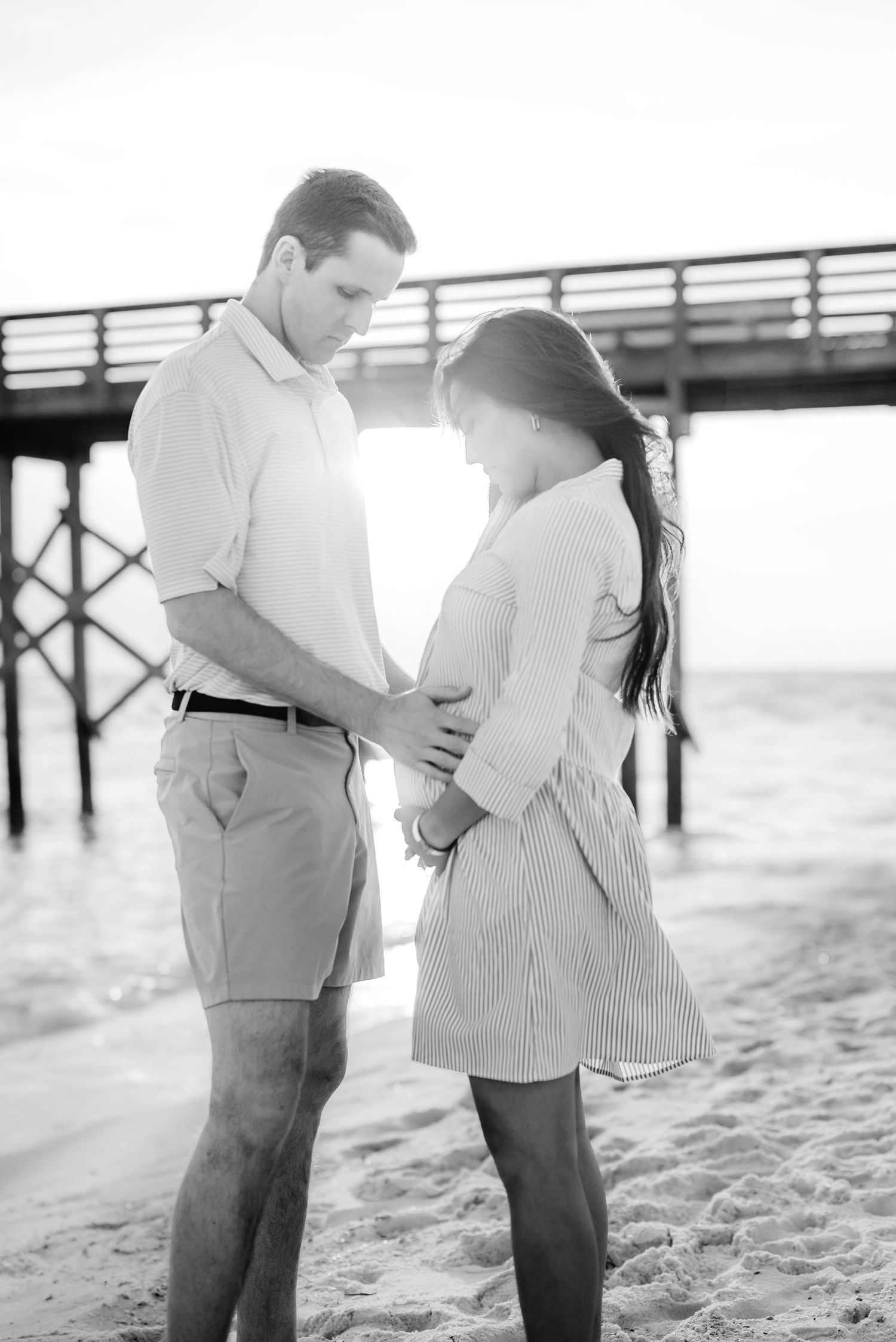 A black and white portrait of a couple sharing an intimate moment on the beach.