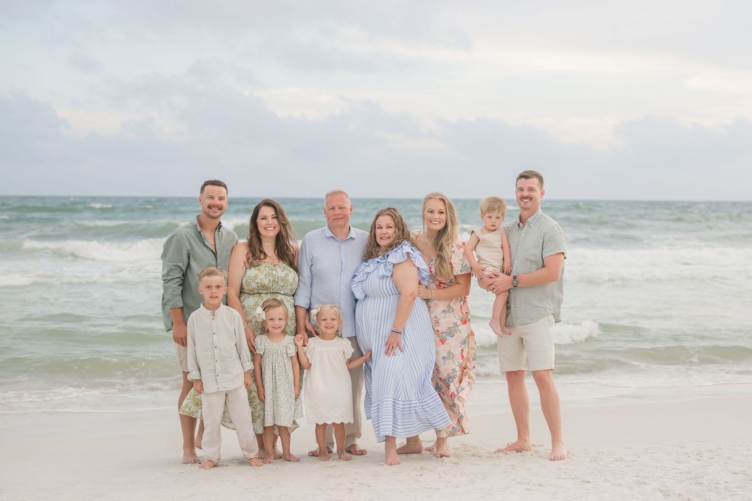 Extended family group photo session on beach with matching neutral colored outfits.