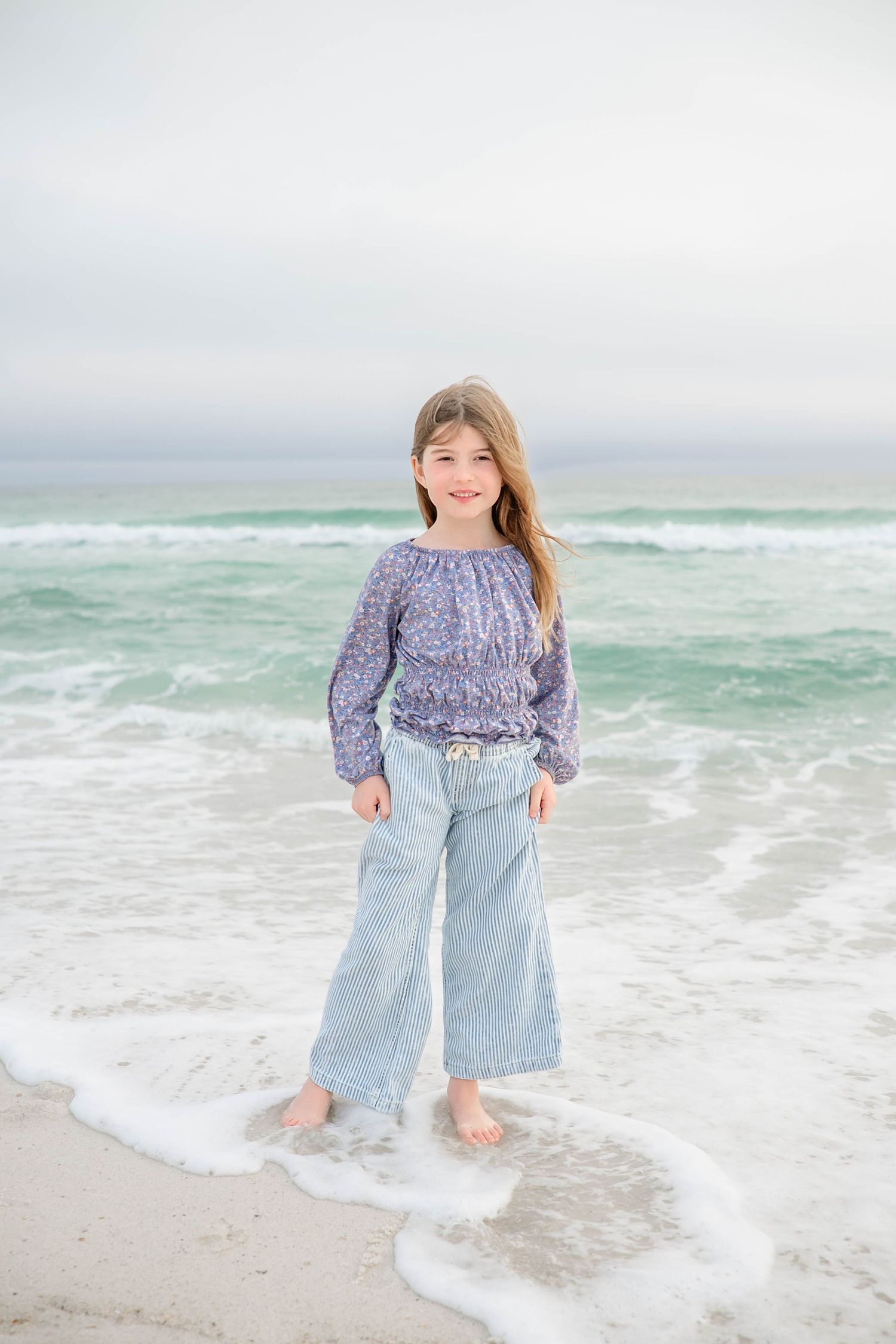 Playful beach portraits with waves washing over bare feet in the sand.