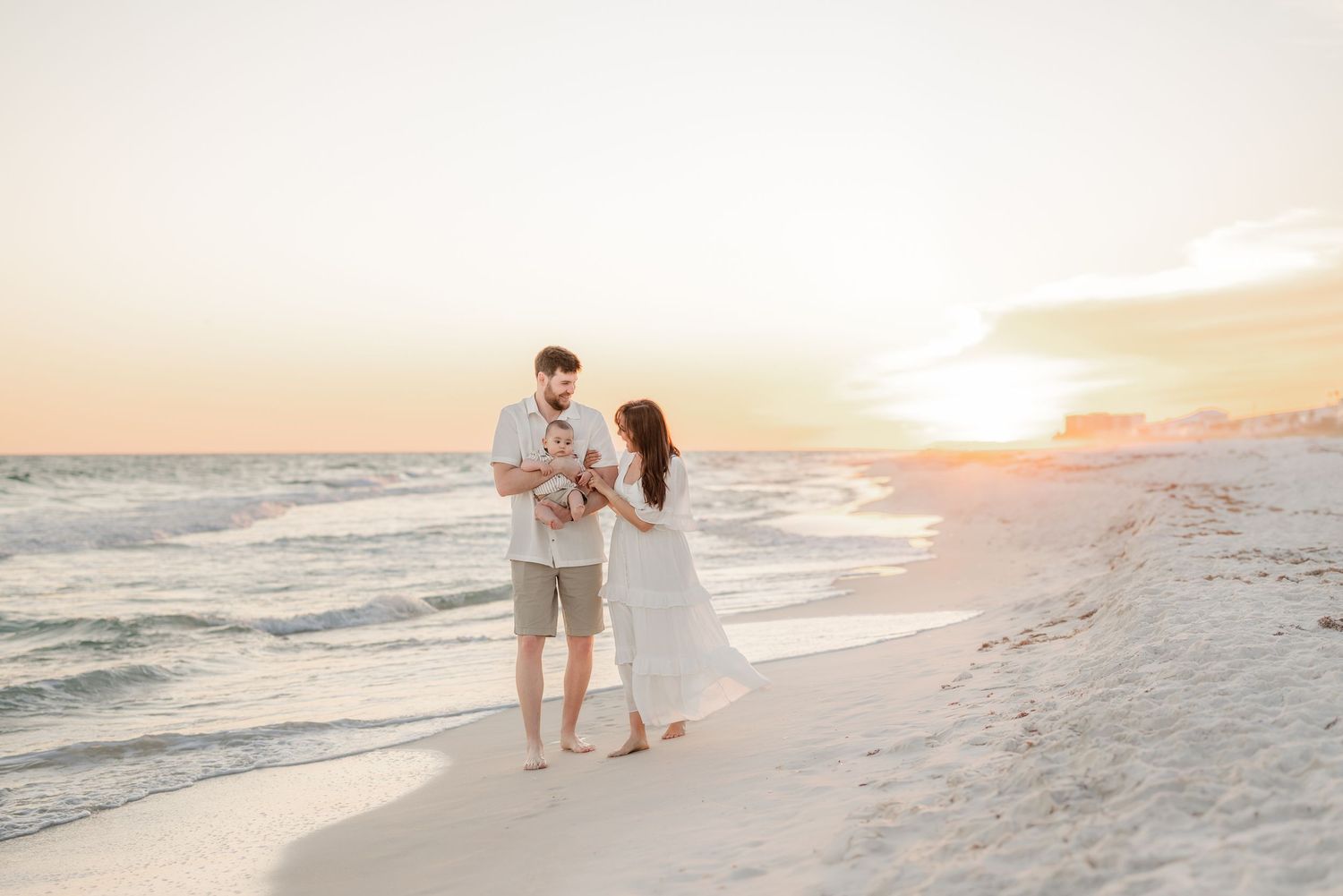 Family walking together along a pristine white sand beach at sunset.