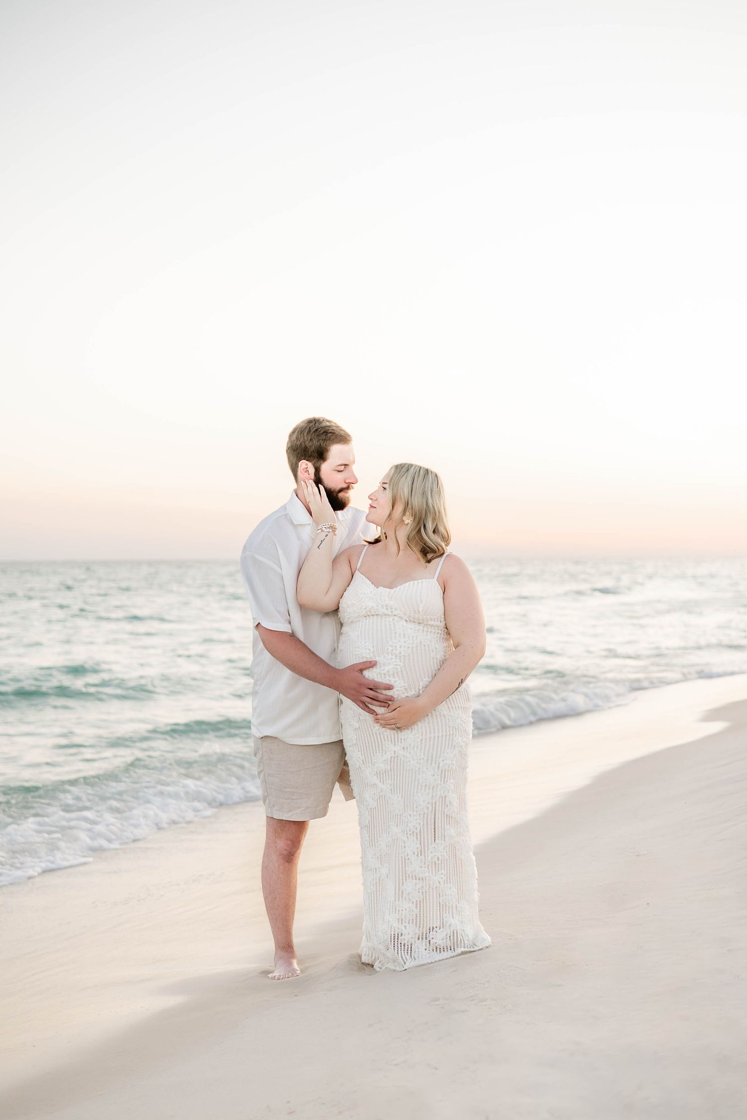 Romantic beach photoshoot with soft lighting and gentle waves at sunset.
