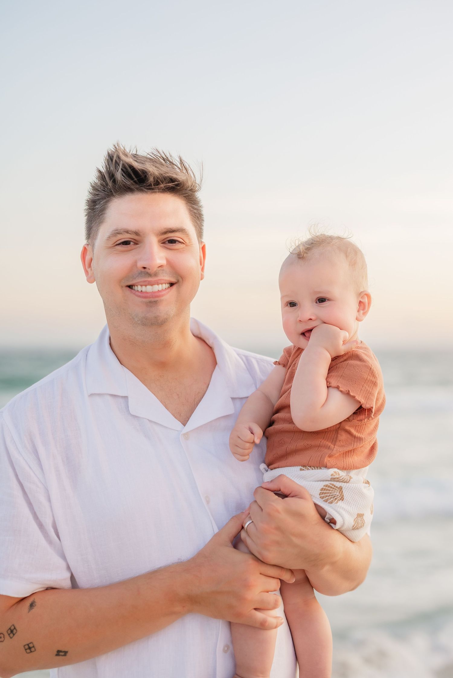 Sweet candid moments captured between parent and baby on sunny beach.