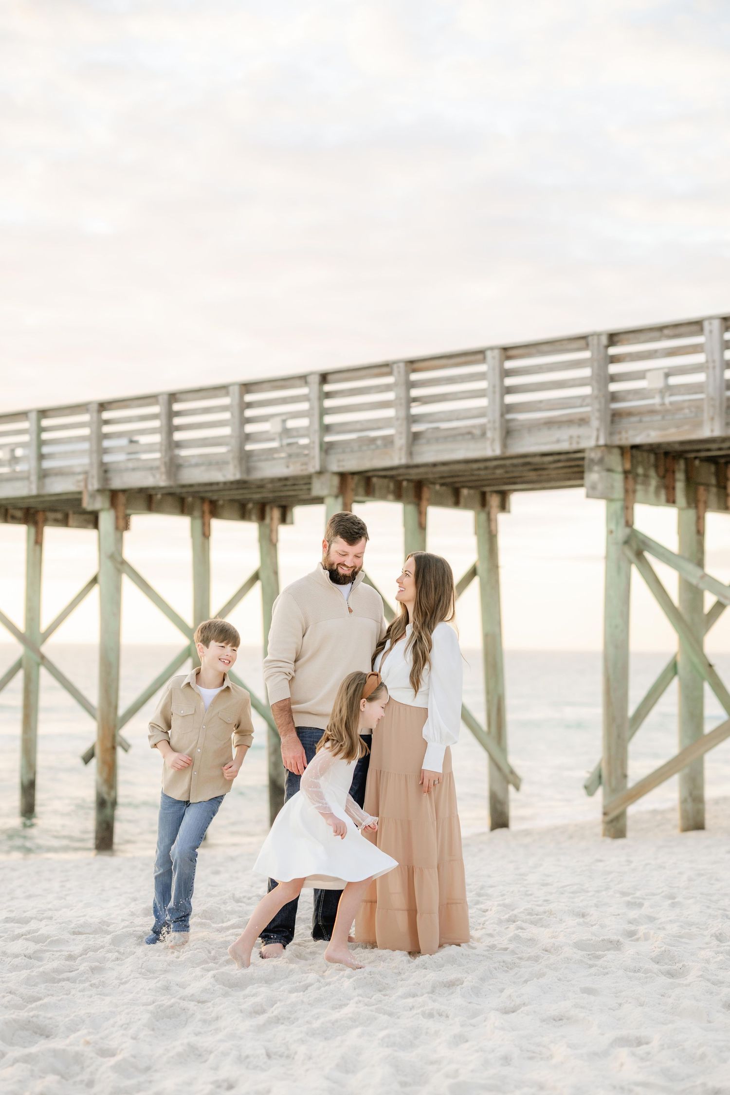 Family of four enjoying a beach photoshoot near a St Andrew's State Park Pier on Panama City Beach at sunset.
