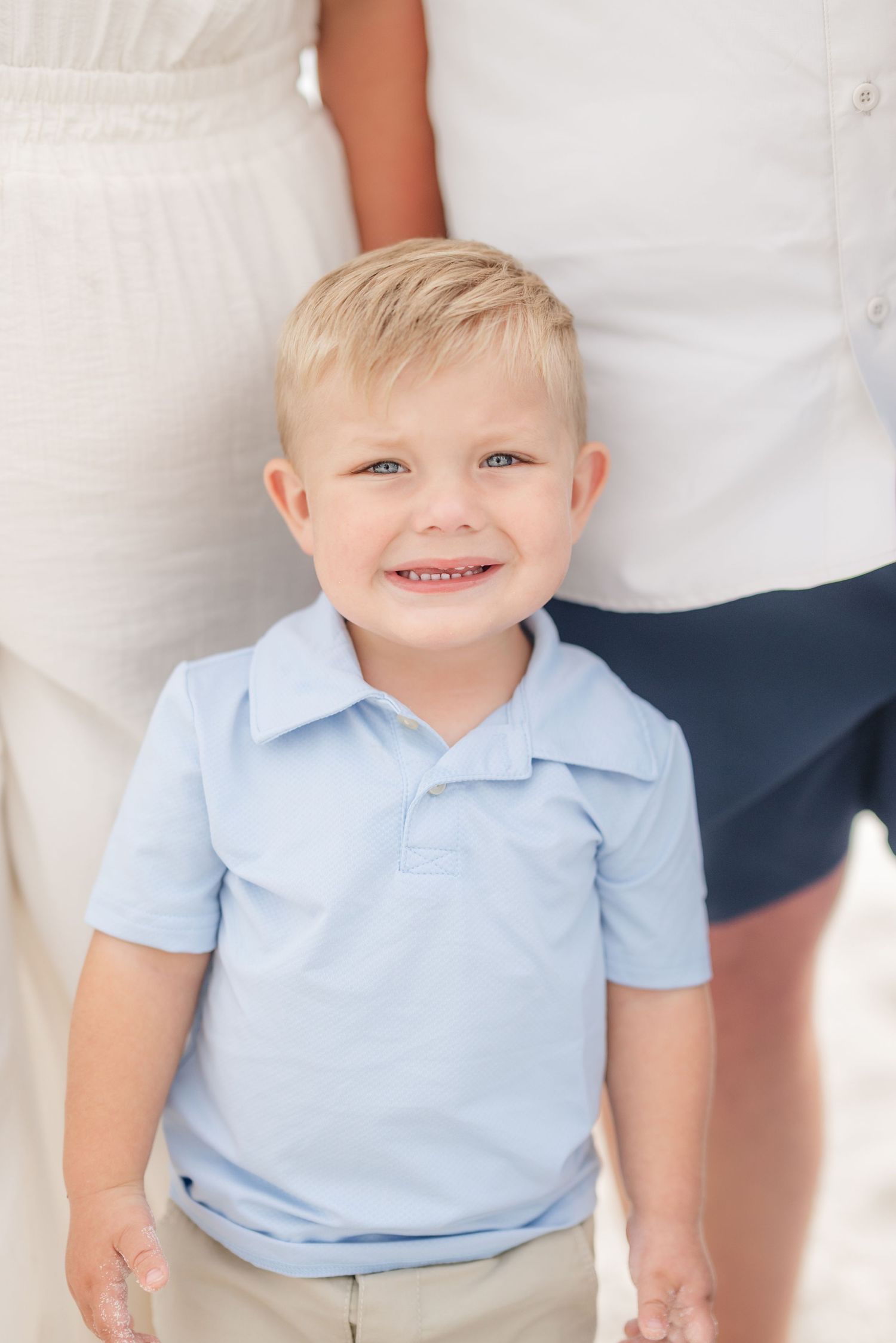 Toddler wearing light blue polo shirt smiles brightly at camera in Panama City Beach, Fl..