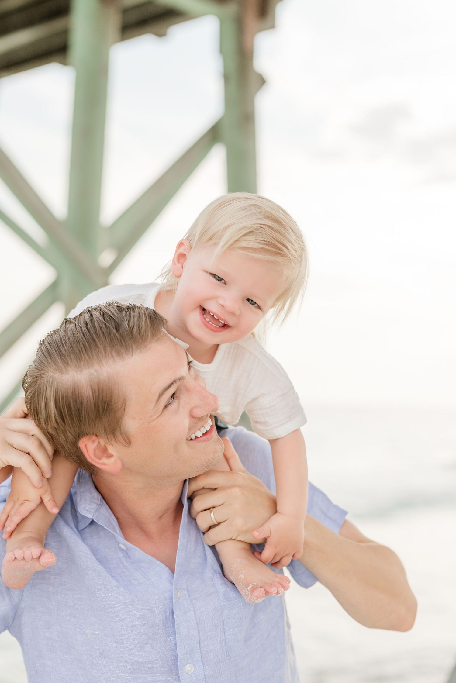 Joyful moments shared under a wooden pier in matching light blue outfits.