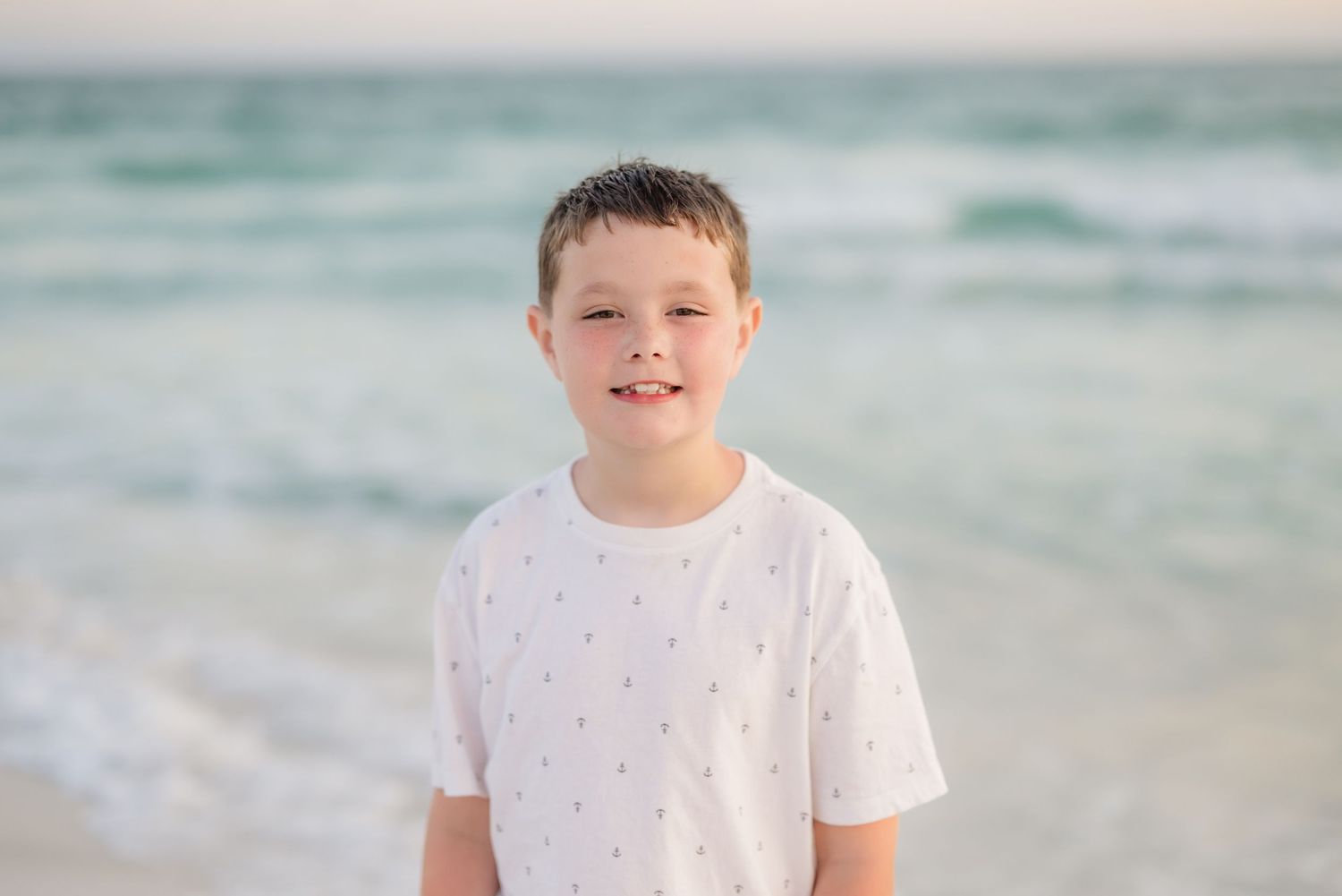 Casual beach portraits with turquoise ocean waves in background in Panama City Beach, Fl..