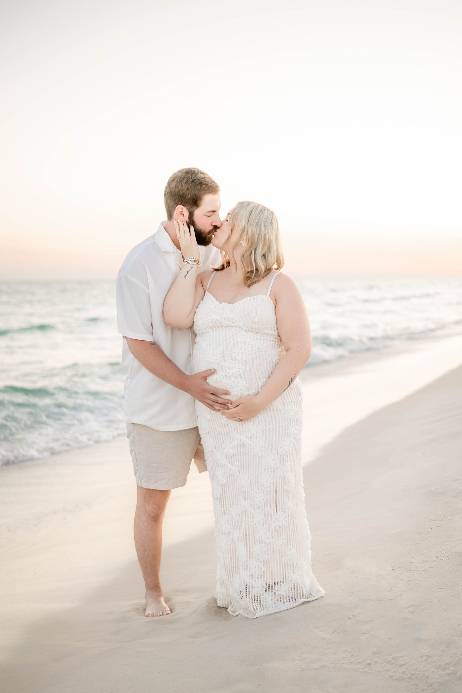 Intimate beach maternity portraits during golden hour with ocean backdrop.
